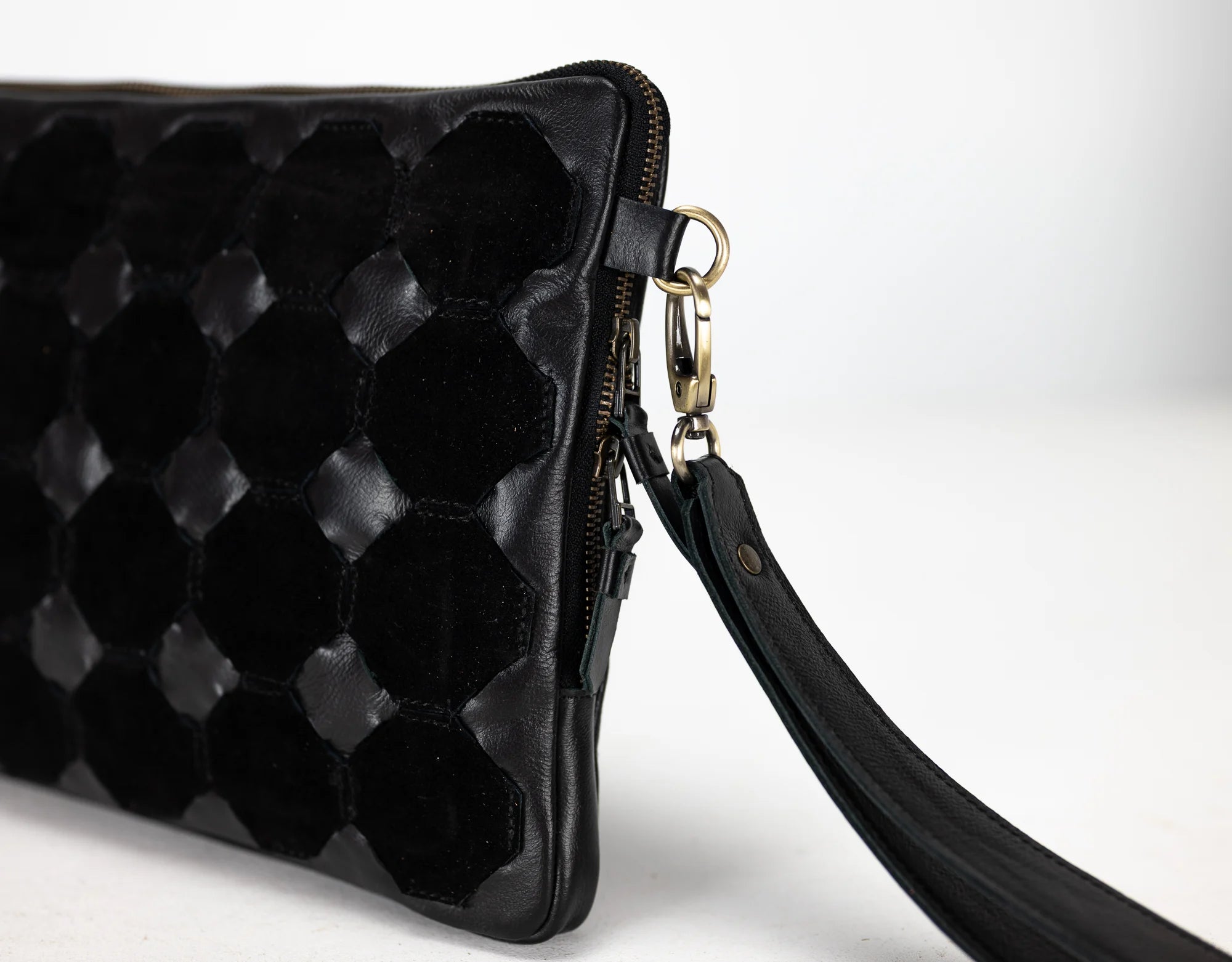 Black quilted clutch bag with a strap on a white background