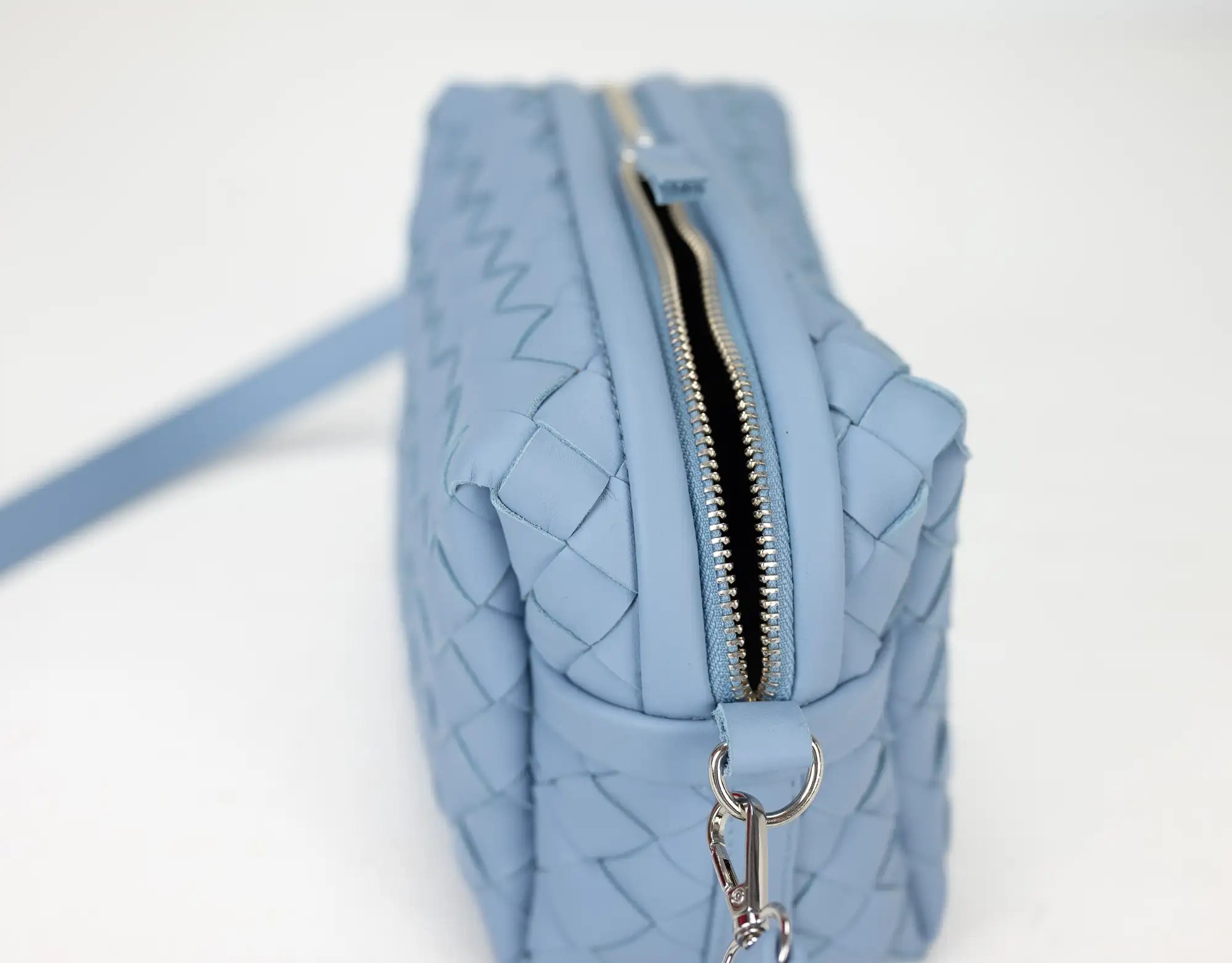 Light blue quilted handbag with a zipper on a white background