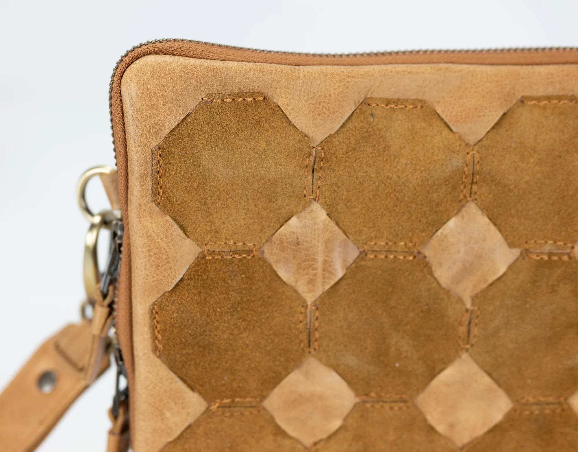 Brown leather clutch with geometric pattern on a light gray background