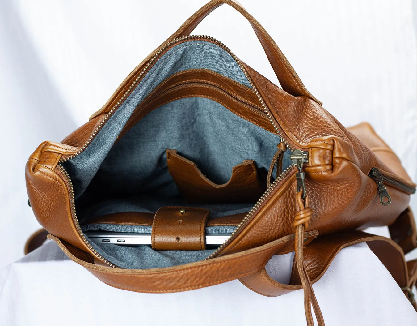Brown leather bag with a visible interior on a white background