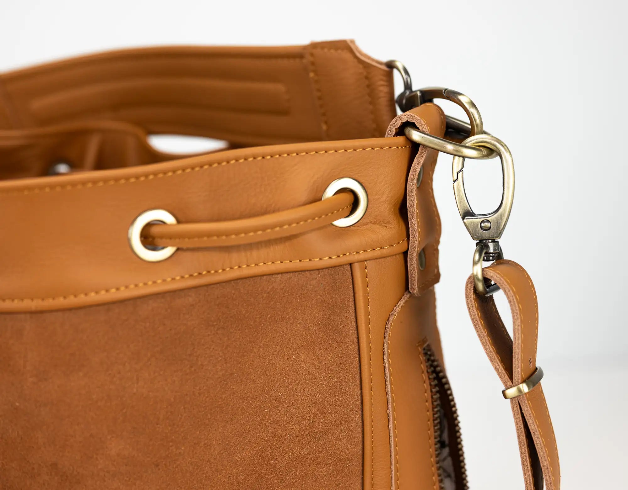 Close-up of a brown leather handbag with gold hardware on a white background
