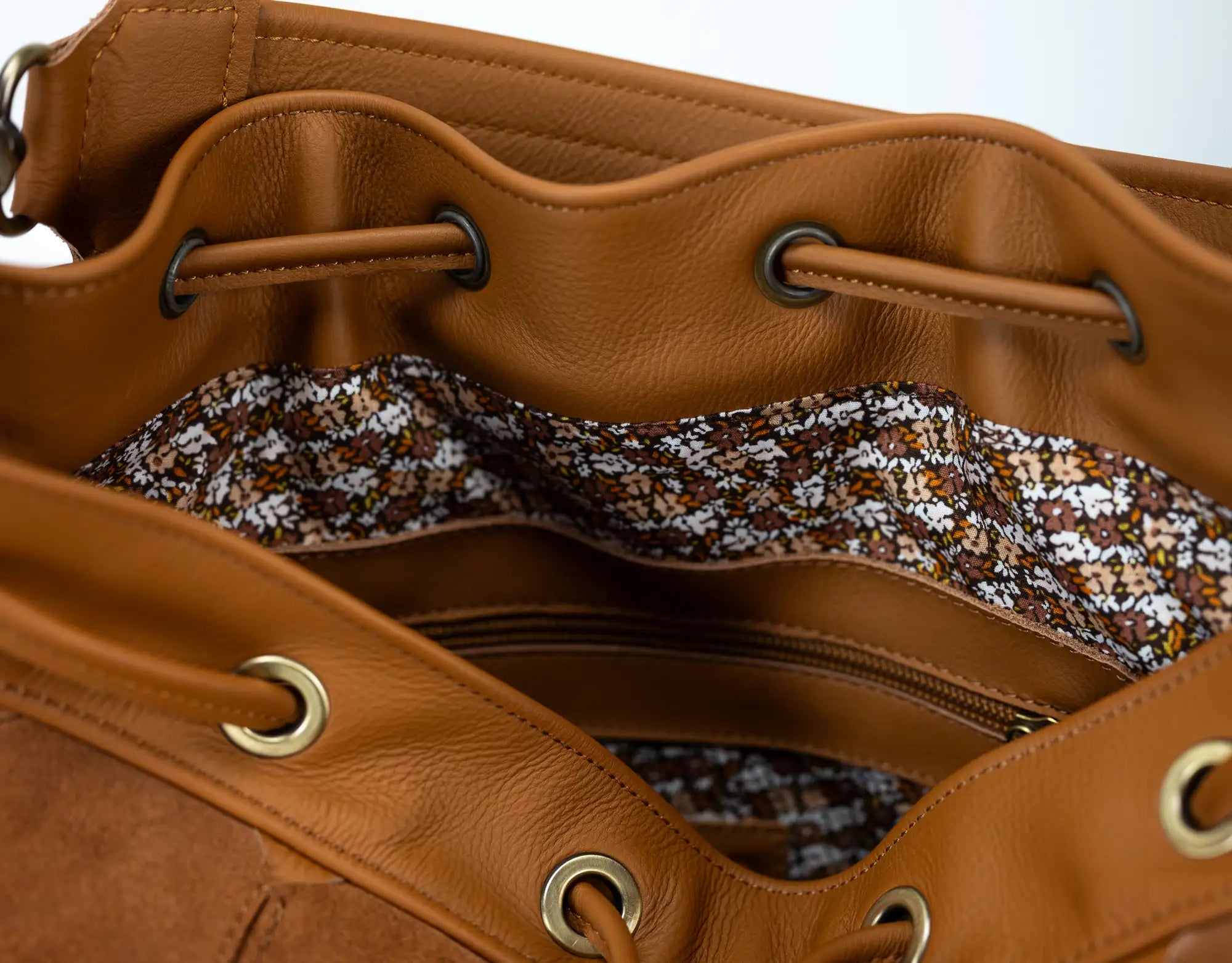 Close-up of a brown leather bag with drawstring and gold accents.
