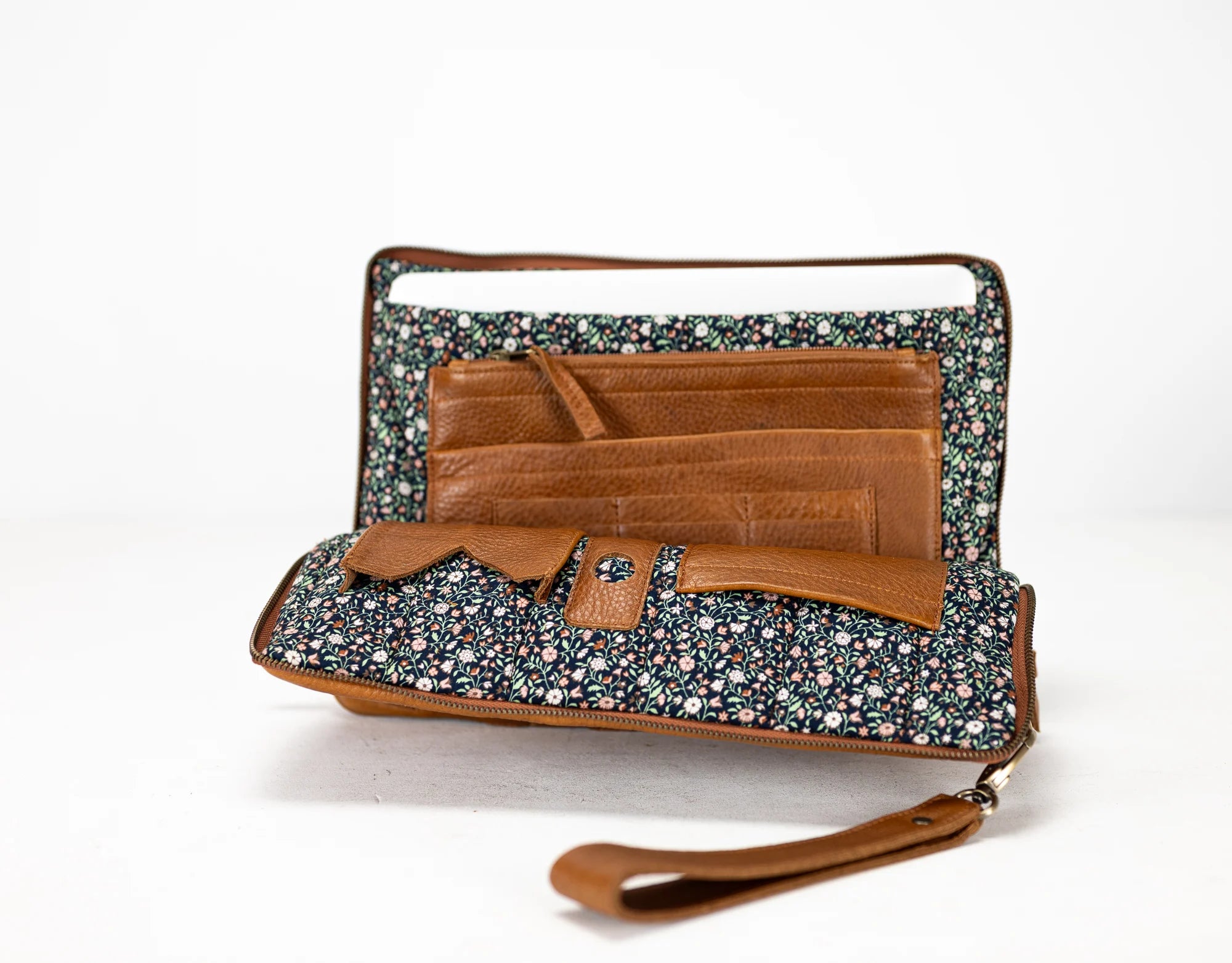 Floral patterned clutch bag with brown leather accents on a white background