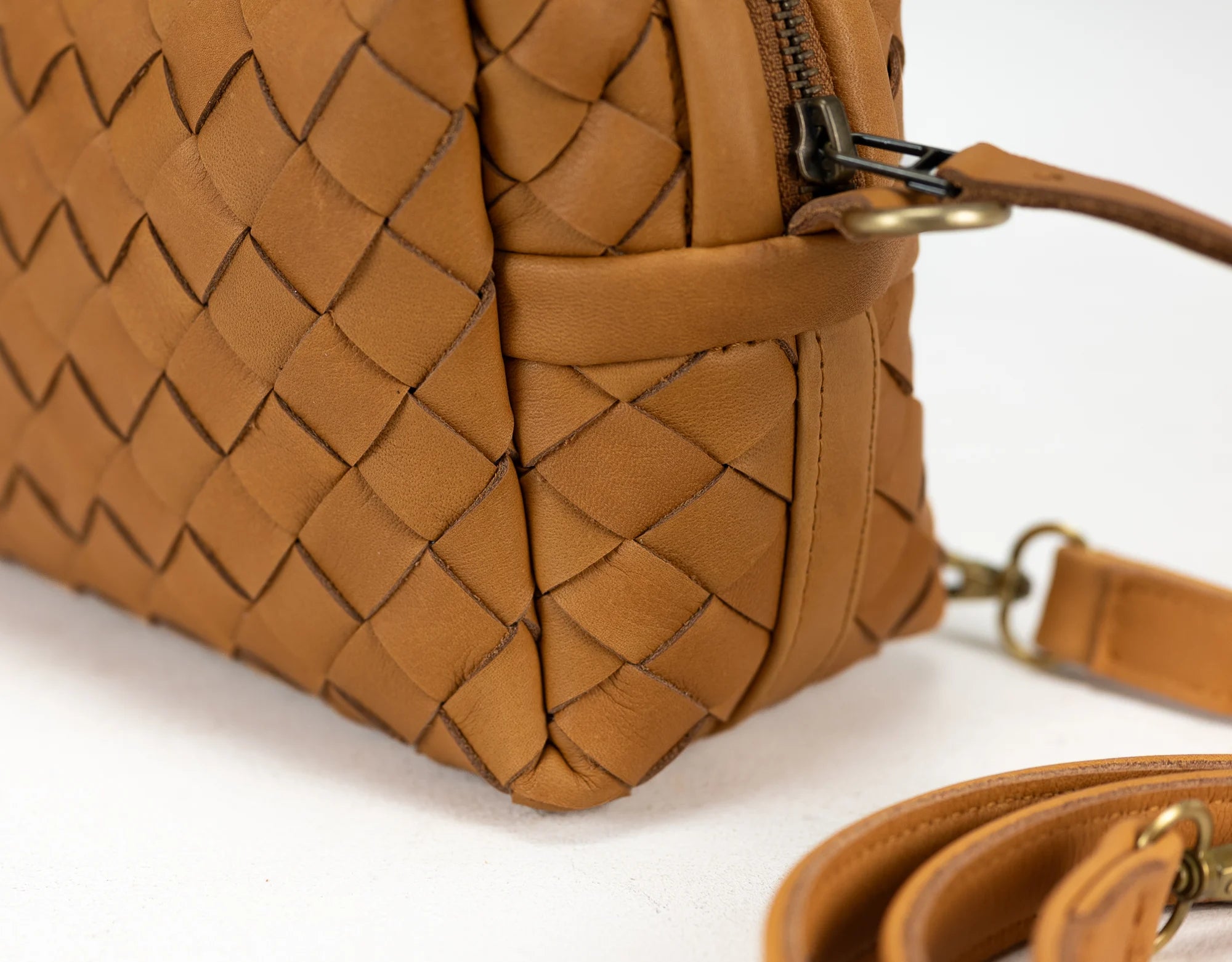 Brown woven handbag with a strap on a white background