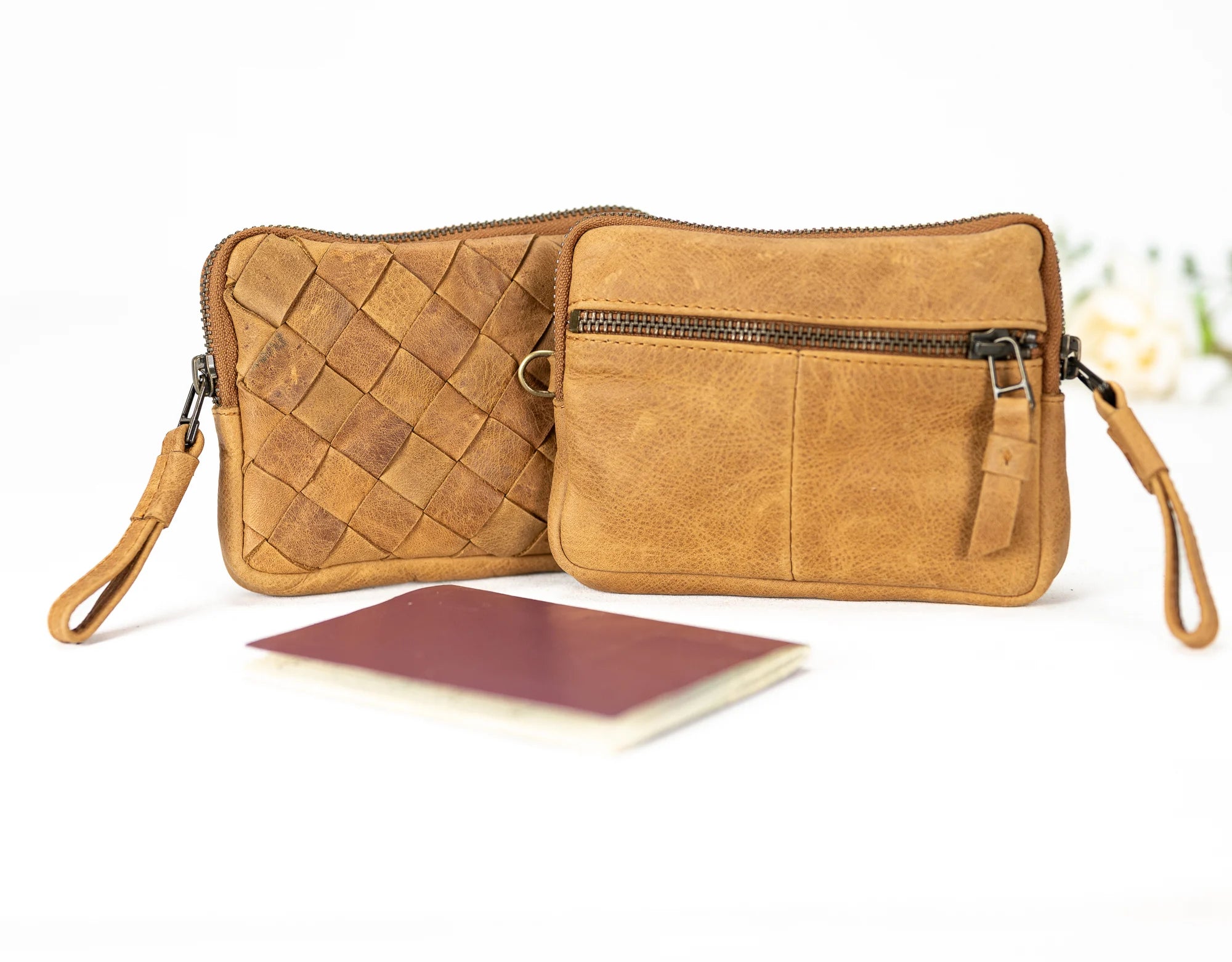Brown leather clutch with woven pattern and wrist strap on a white background