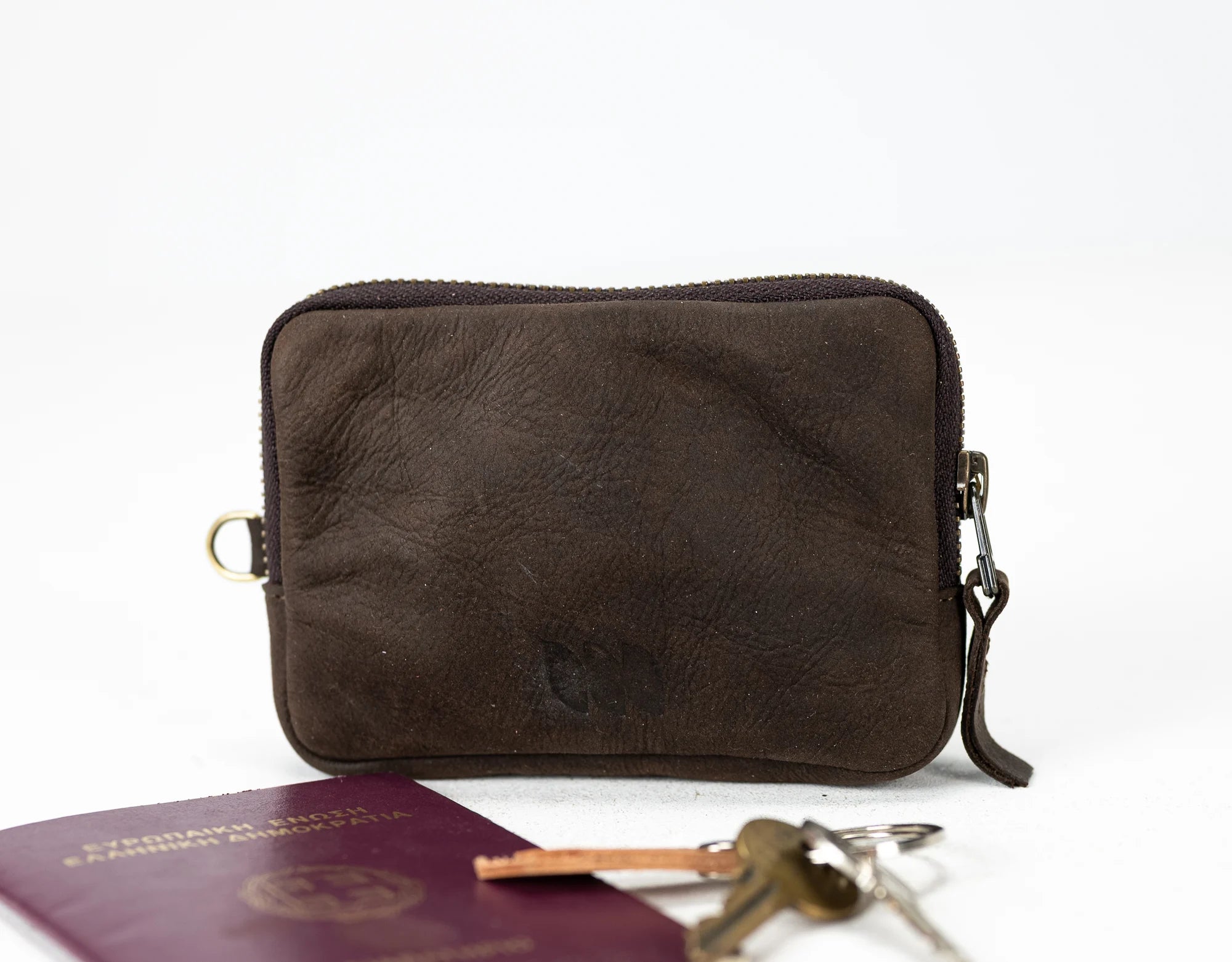 Brown leather pouch with keys and passport on a white background