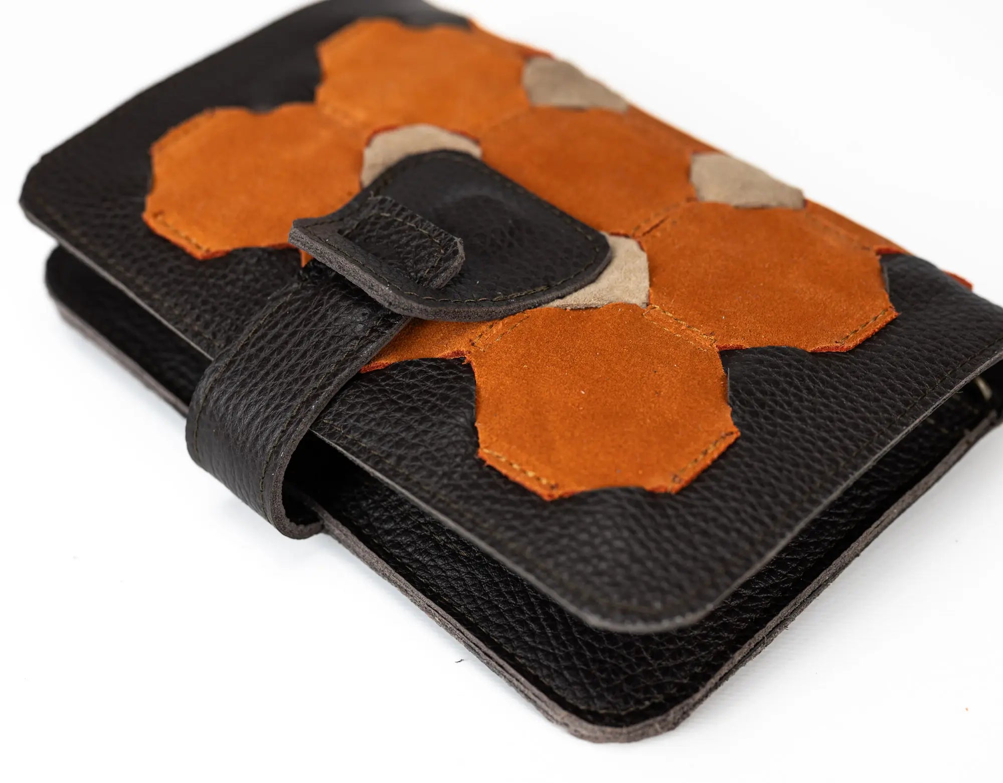 Brown leather wallet with orange and beige hexagonal patches on a white background