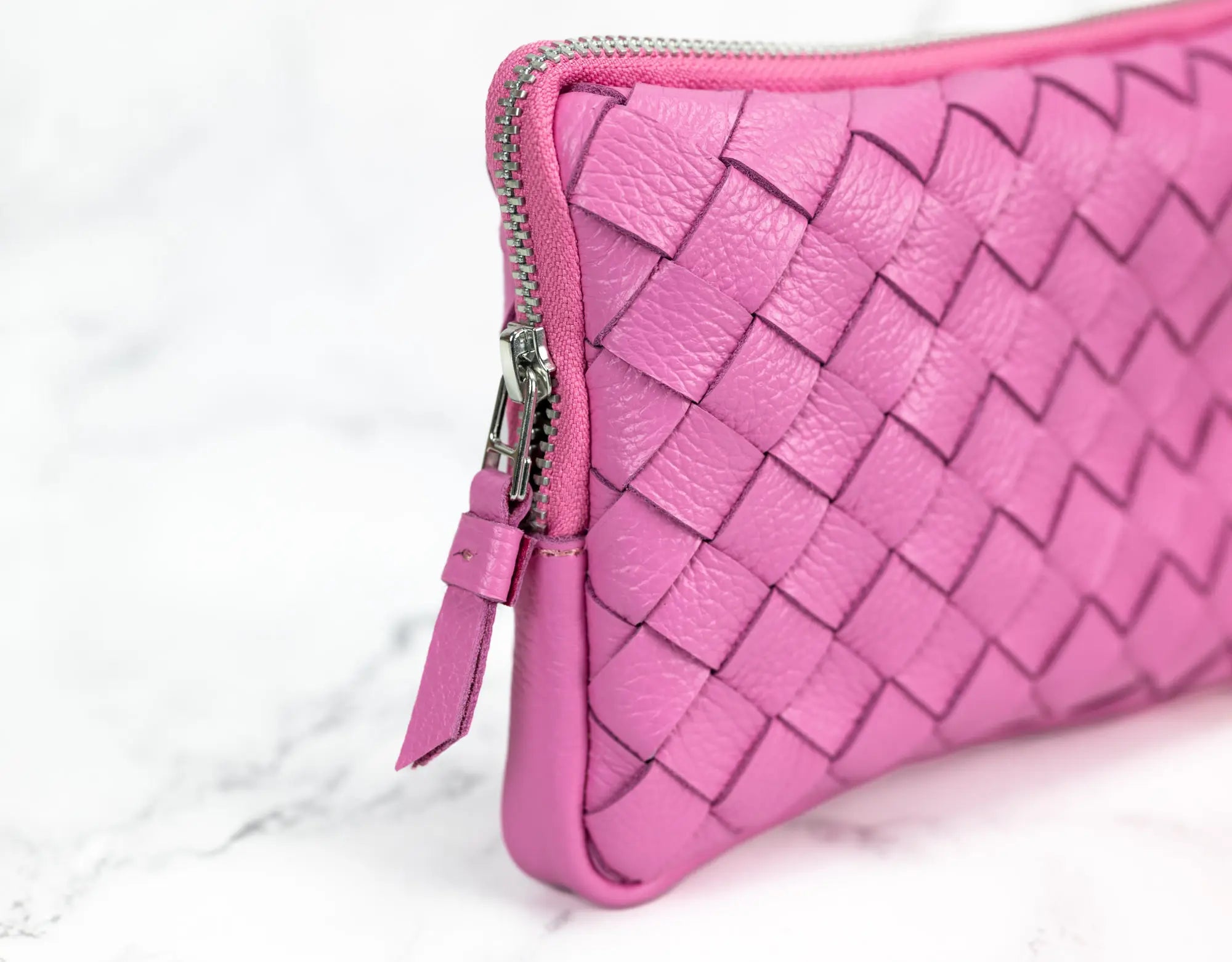 Pink woven clutch bag on a white background