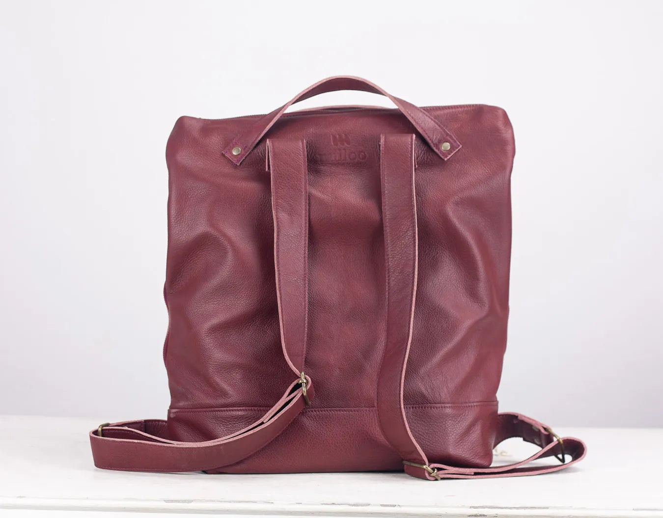Maroon leather backpack on a white background