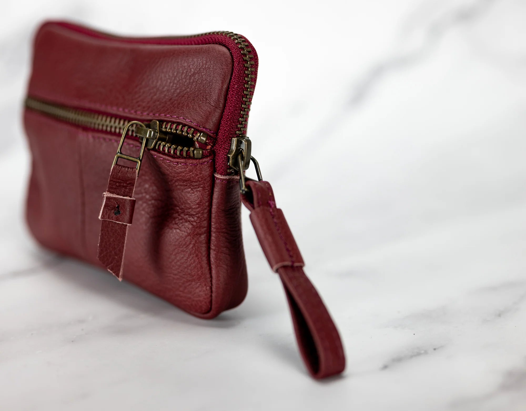 Red leather clutch with a strap on a white background