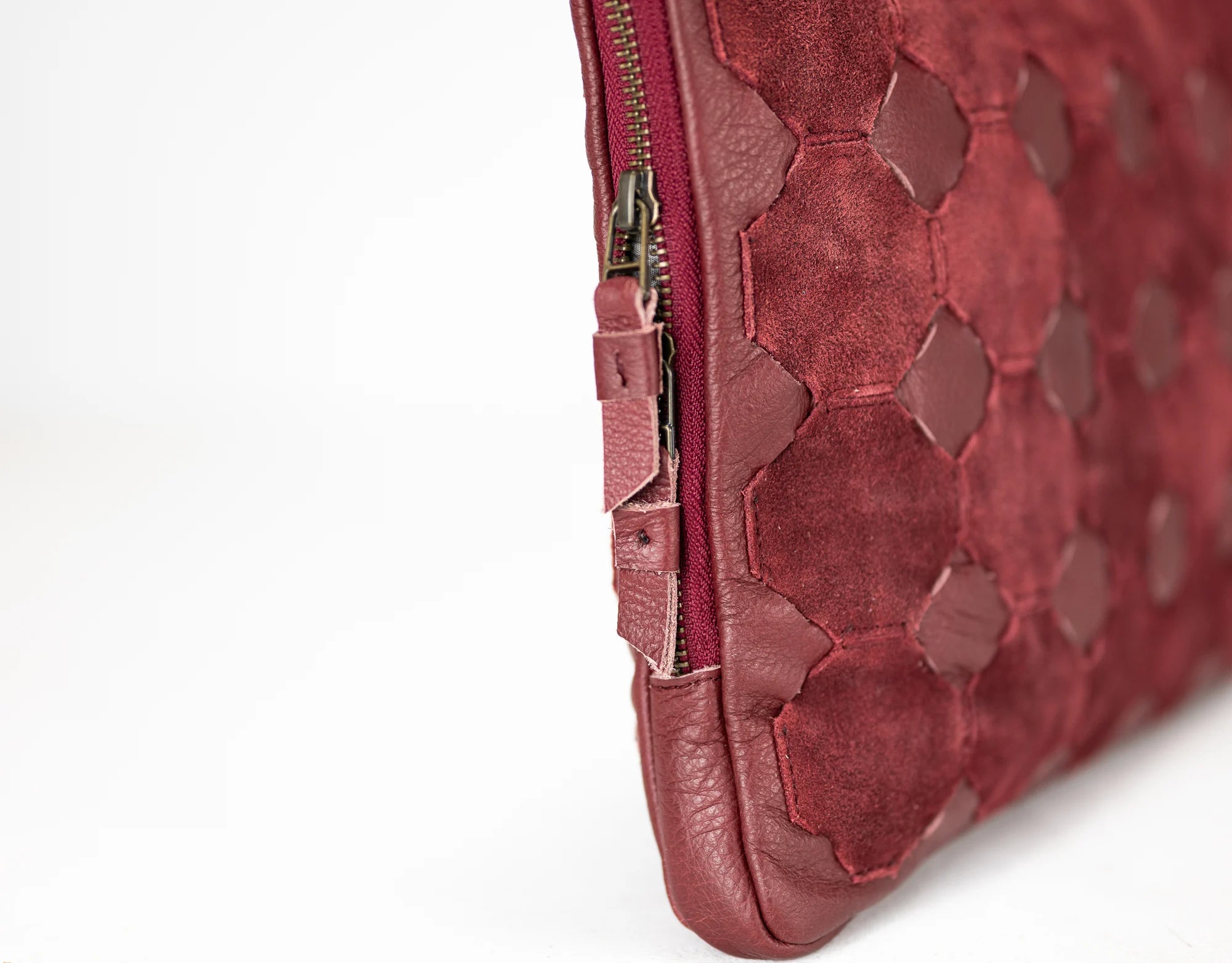 Close-up of a red textured clutch bag with a zipper on a white background