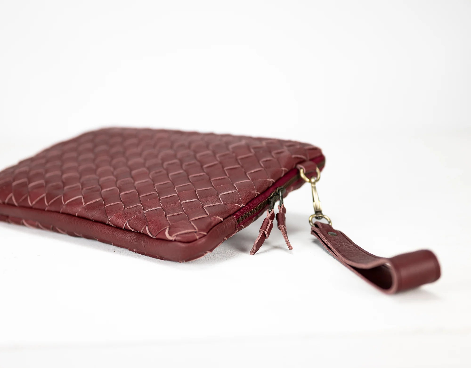 Maroon woven leather clutch bag on a white background