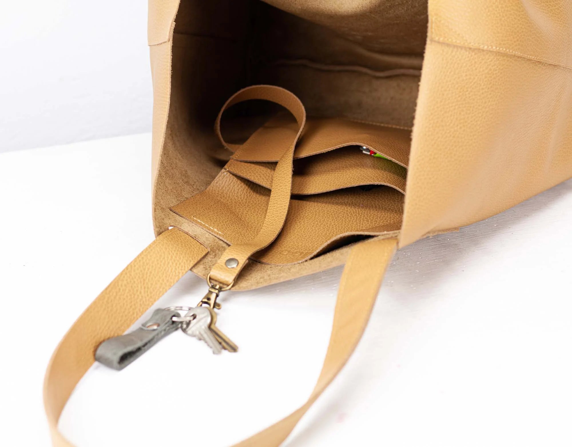 Close-up of a tan leather bag with a strap