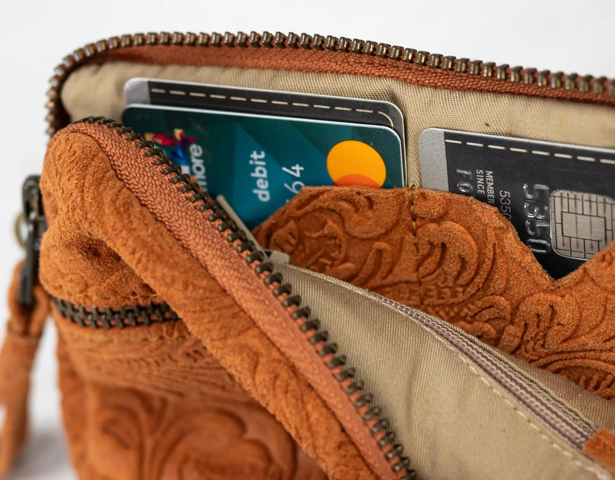 Brown leather wallet with embossed designs, containing cards and a coin purse.