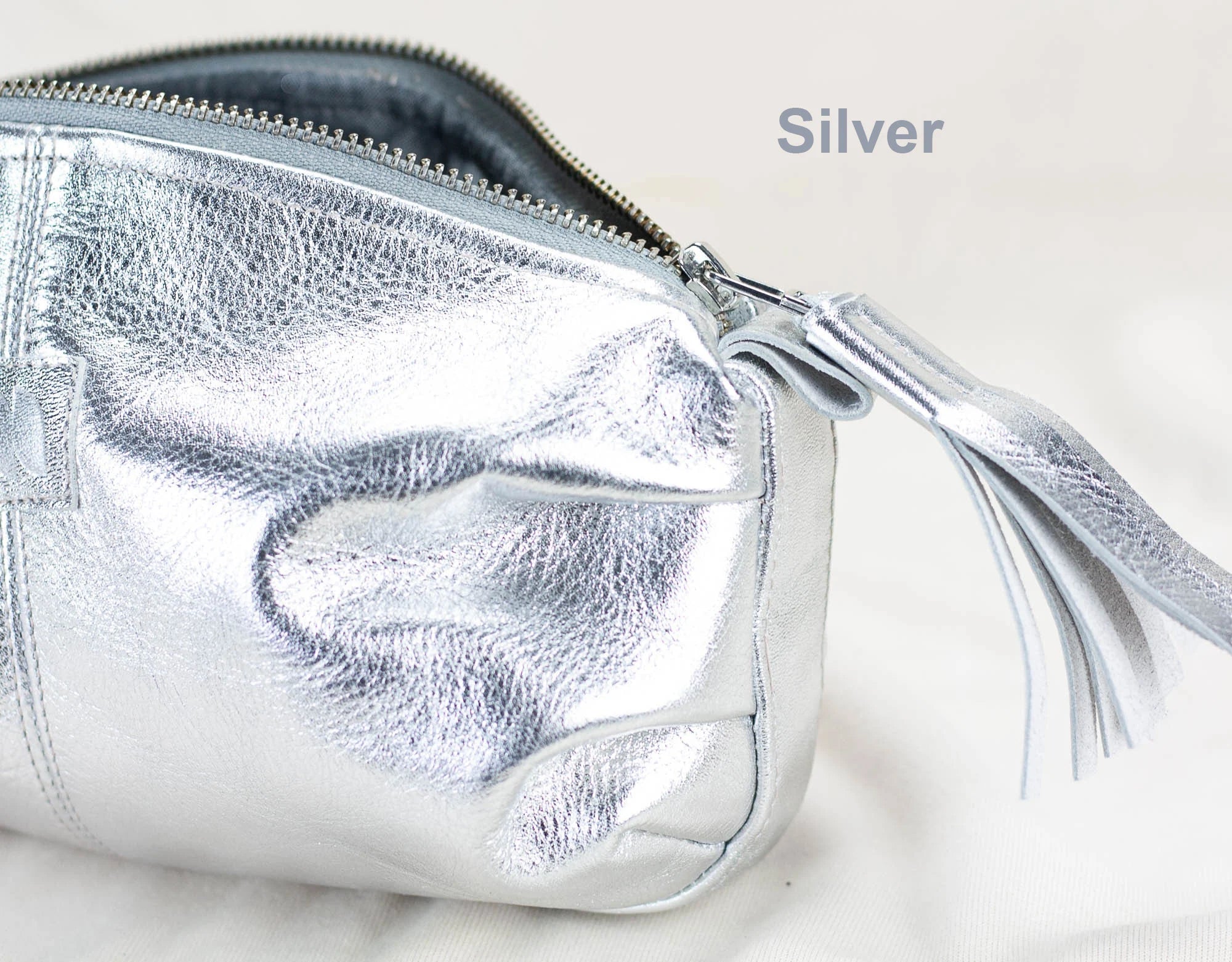 Silver clutch bag with a tassel on a light background
