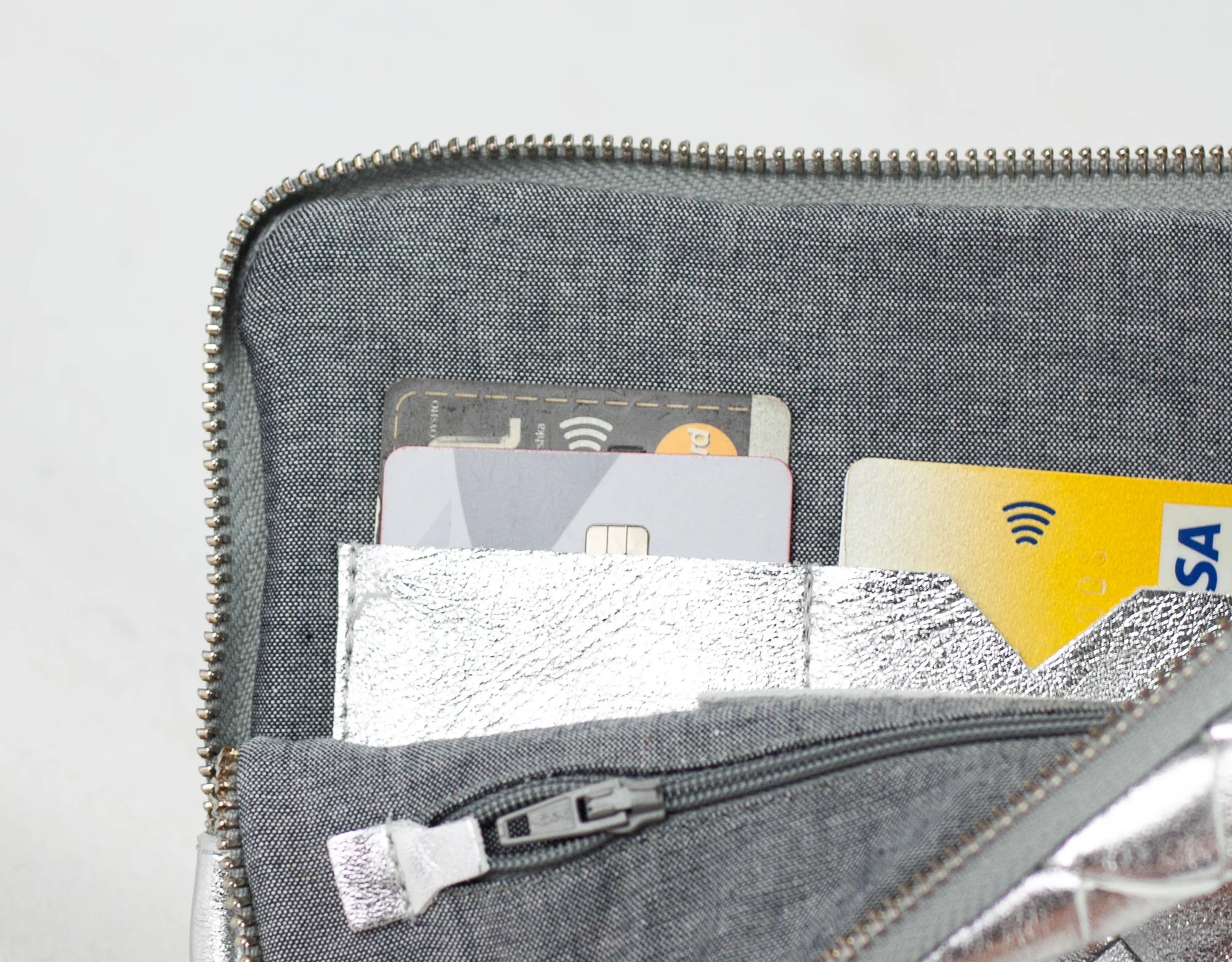 Gray zippered pouch with cards inside on a light gray background