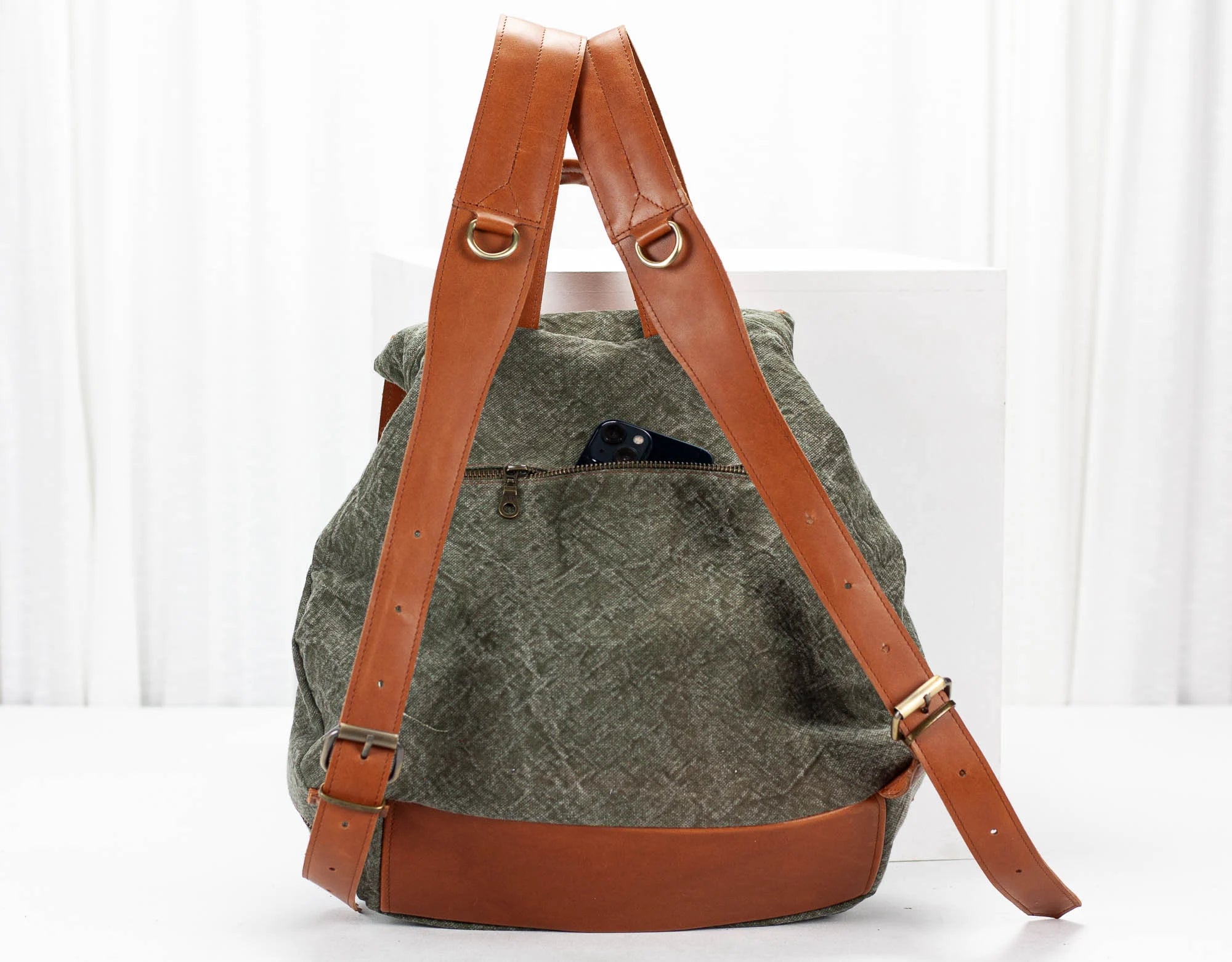 Green backpack with brown leather straps on a white background
