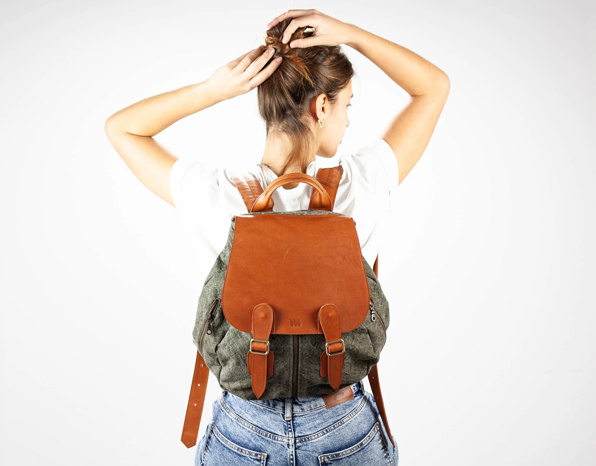 Person wearing a brown leather backpack on a plain background