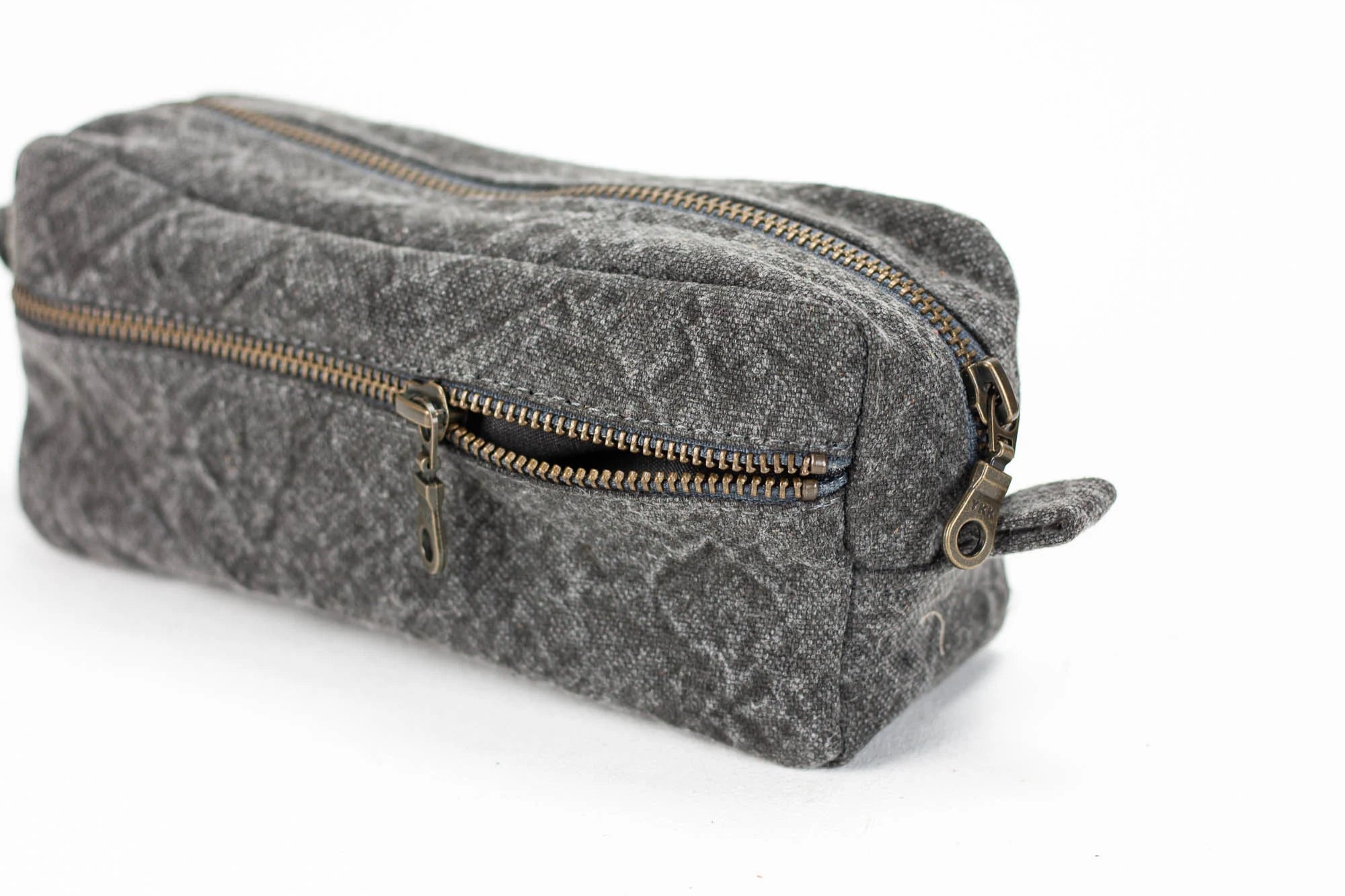 Gray textured toiletry bag with gold zipper on a white background