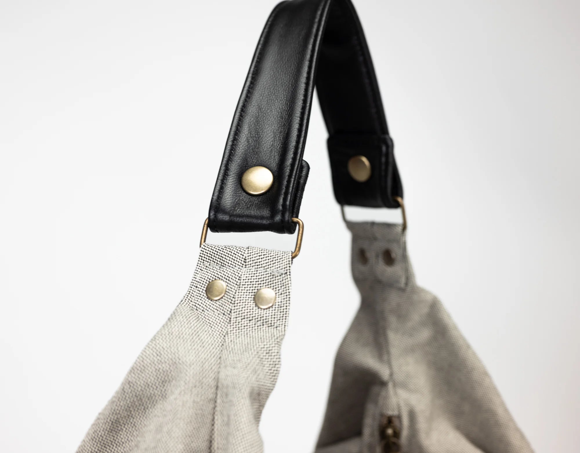 Close-up of a gray bag with black leather handle on a white background