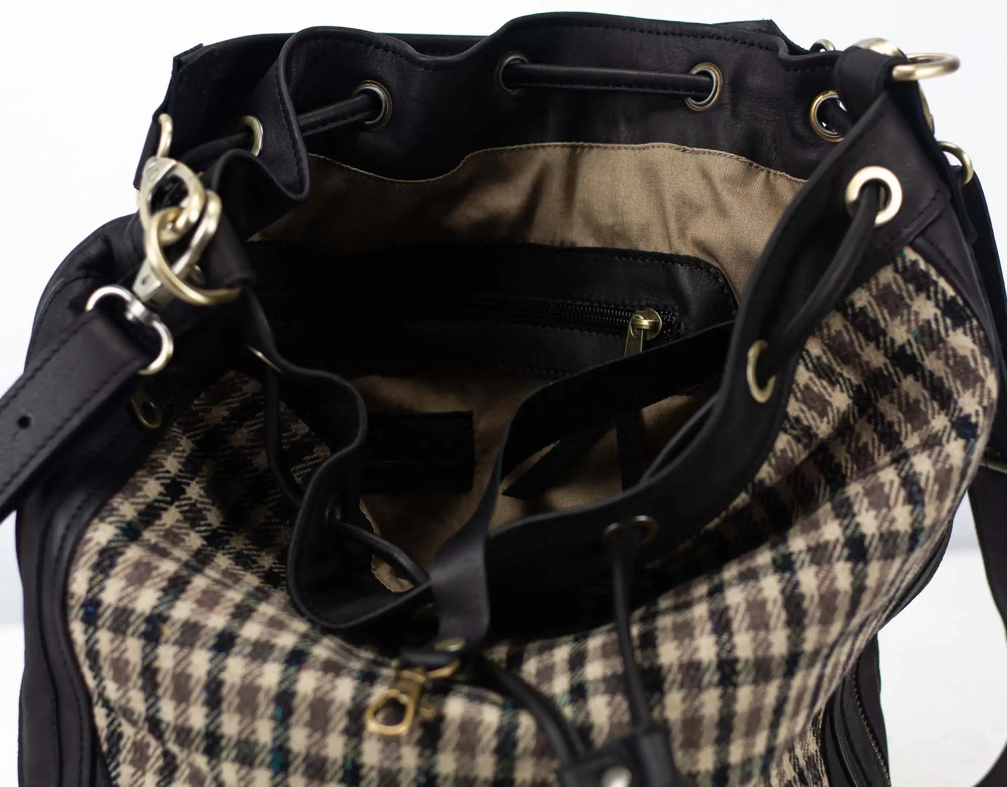 Plaid patterned bag with black drawstring and gold metal accents on a white background