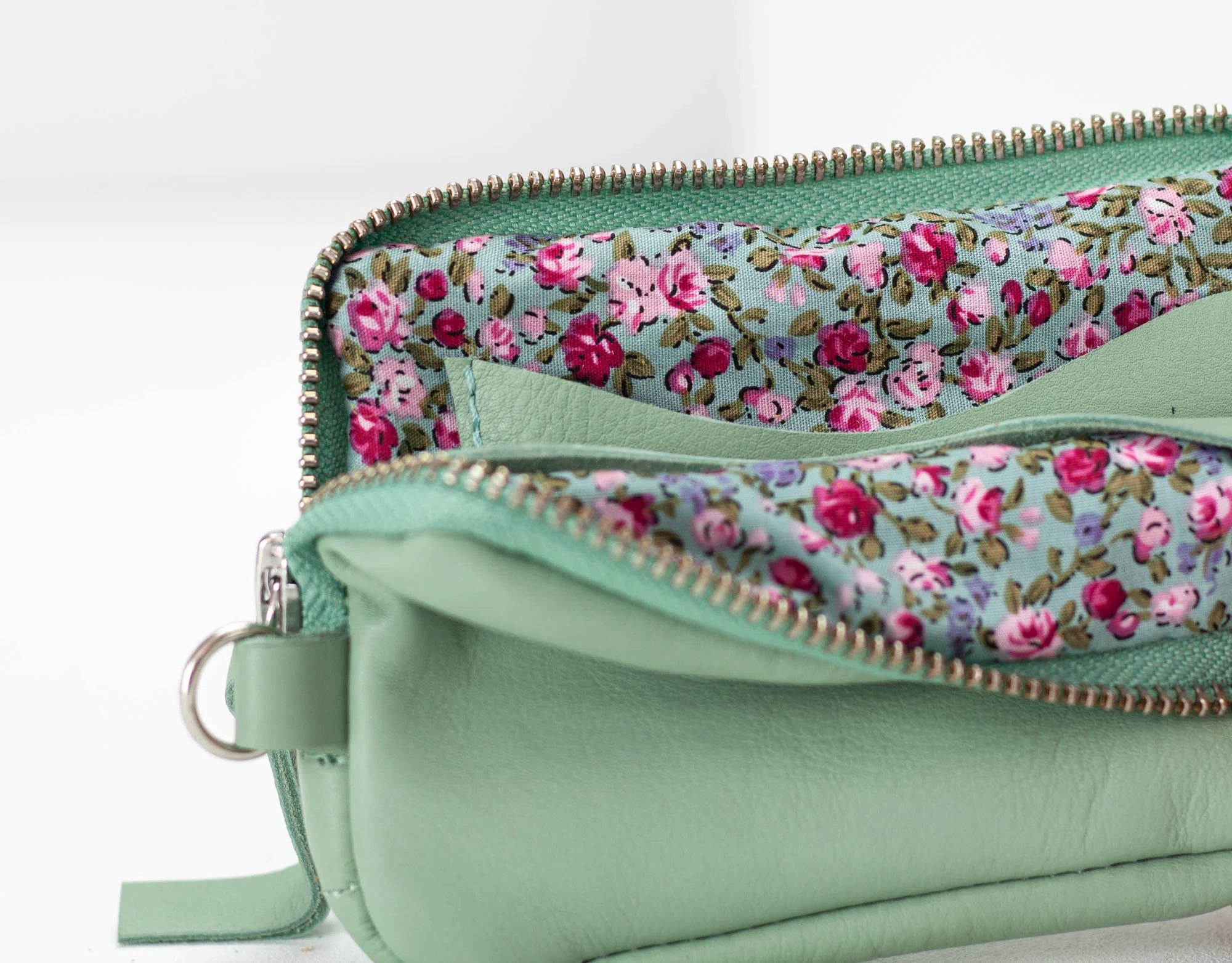 Light green clutch with floral lining on a white background