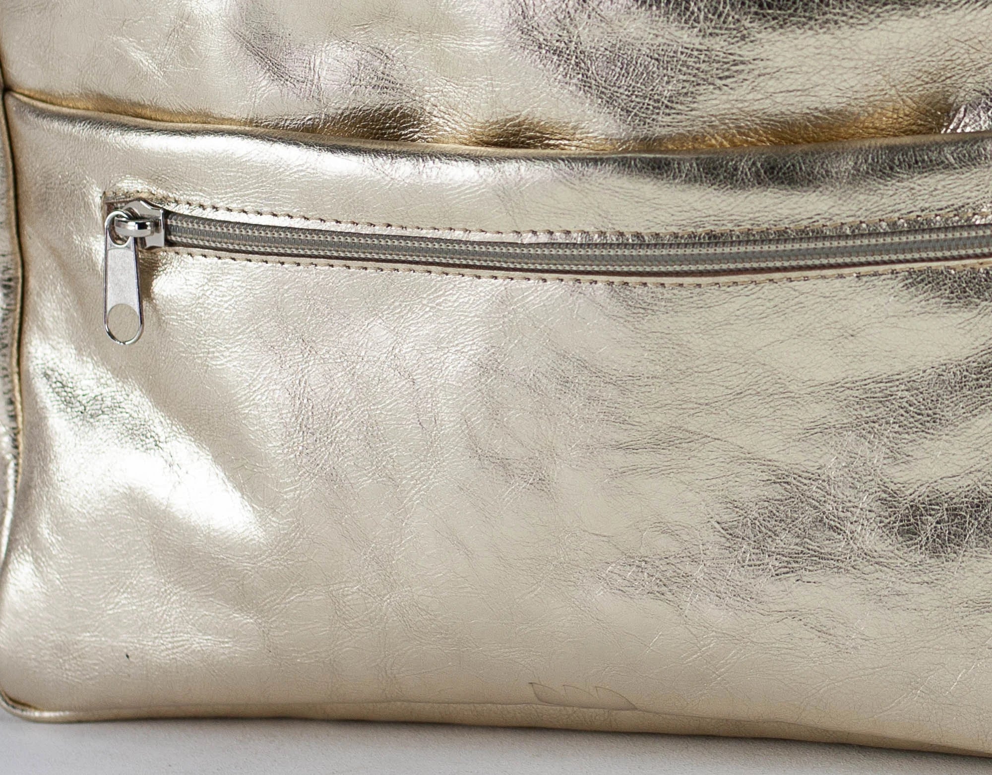 Close-up of a metallic gold bag organizer with a zipper on a light background