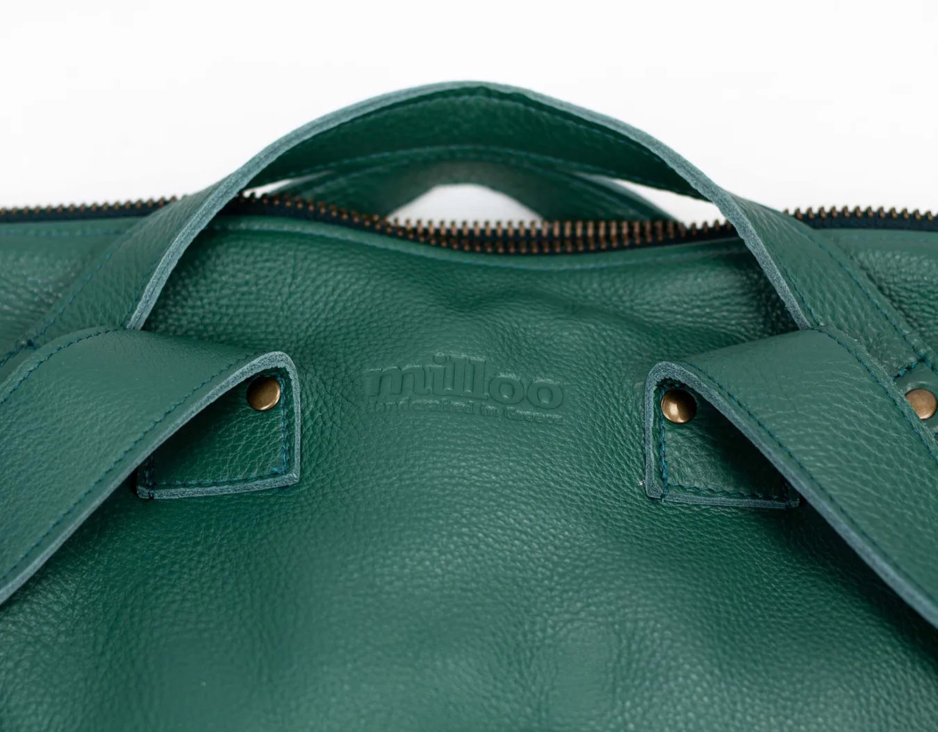 Close-up of a green leather bag with visible branding on a white background