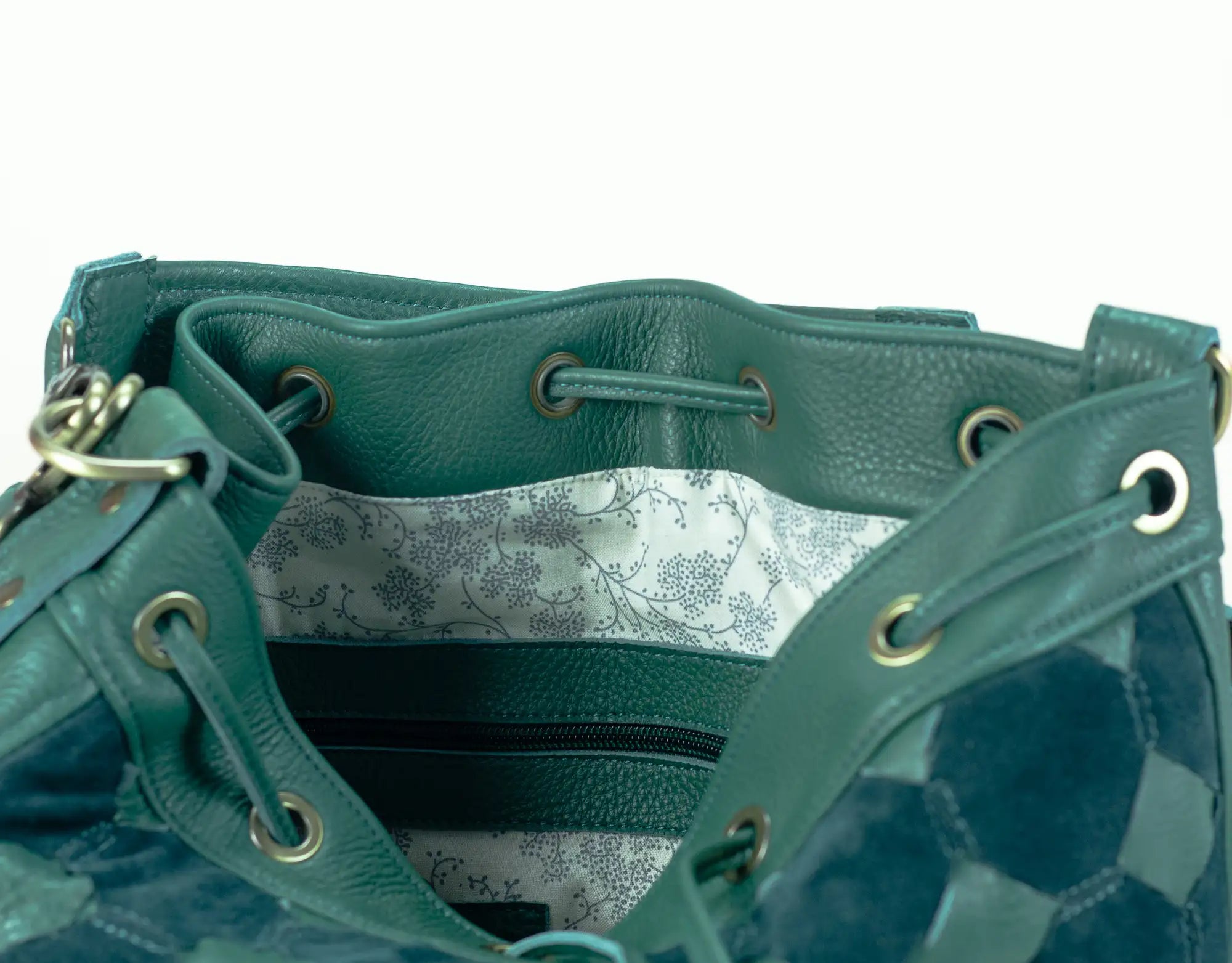 Teal leather handbag with floral interior lining on a white background