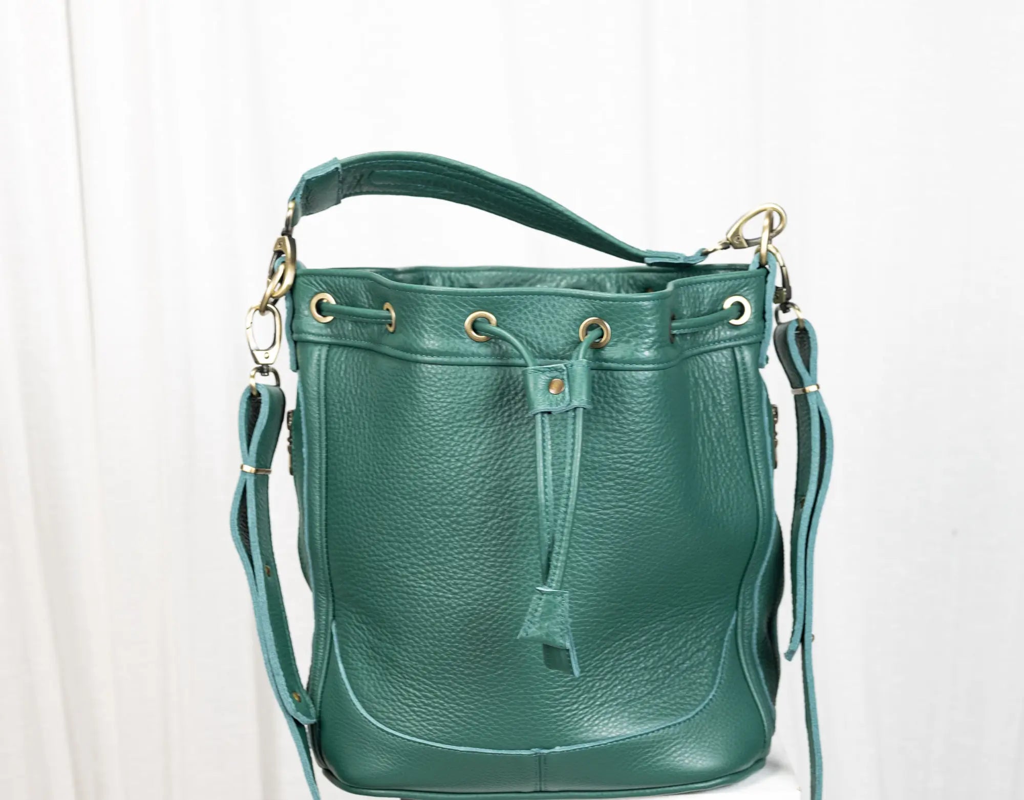 Green leather handbag with gold accents on a white background