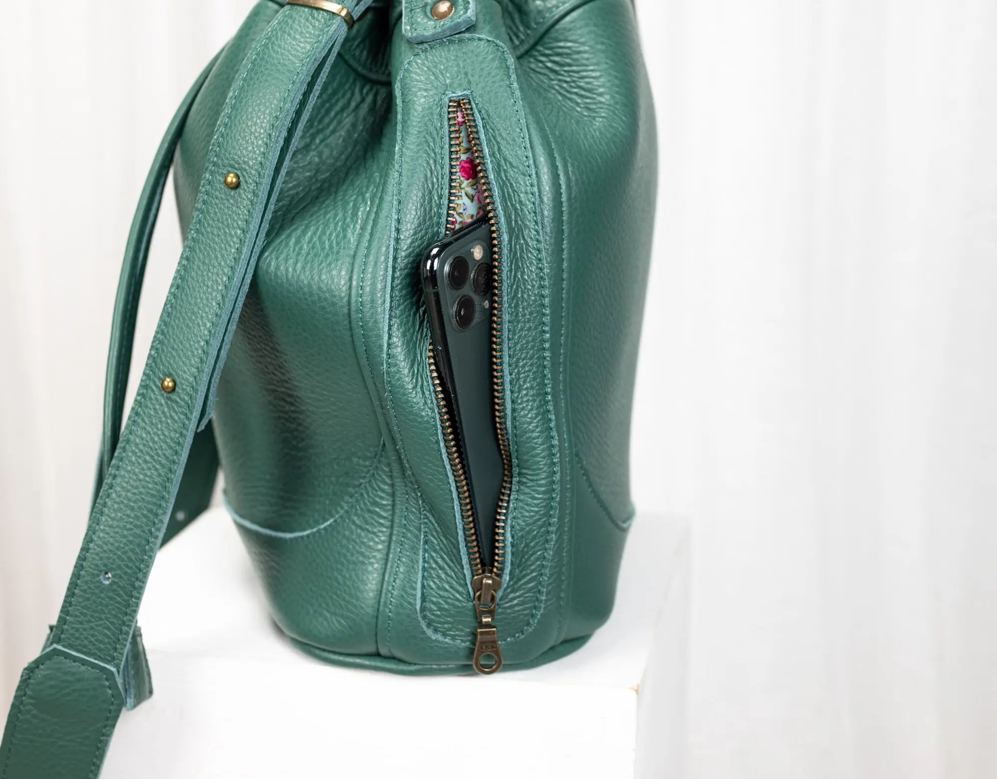 Green leather handbag with a zipper on a white background