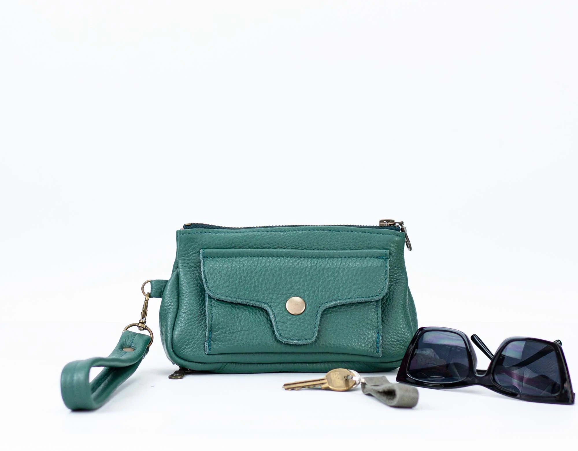 Teal handbag with sunglasses and keys on a white background