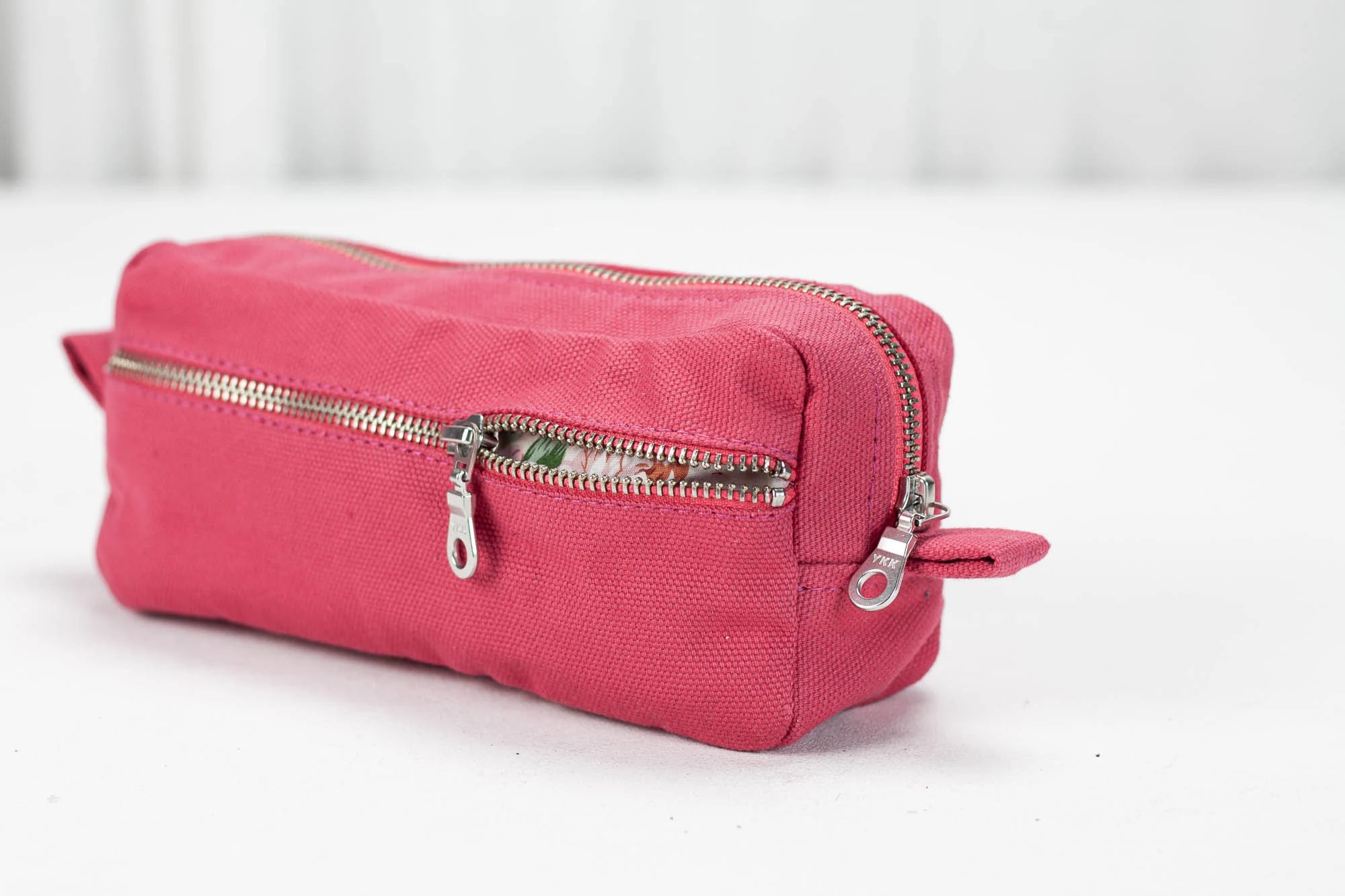 Pink cotton toiletry bag with a zipper on a white background