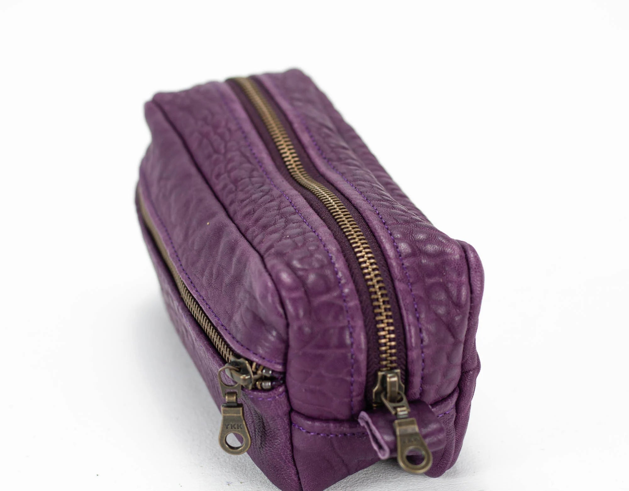 Purple textured pouch with gold zippers on a white background