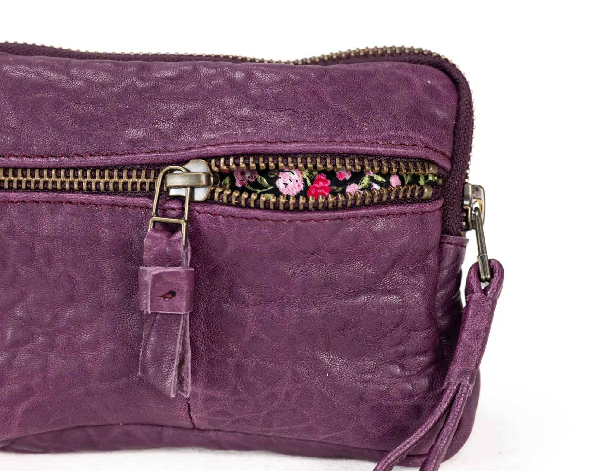 Purple leather bag with floral embroidery on a white background