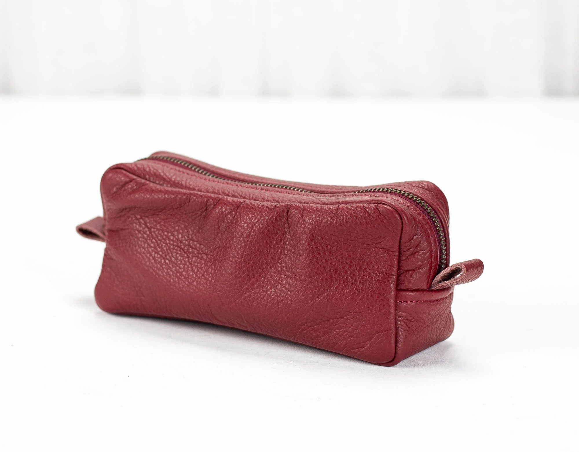 Red leather toiletry bag with a zipper on a white background