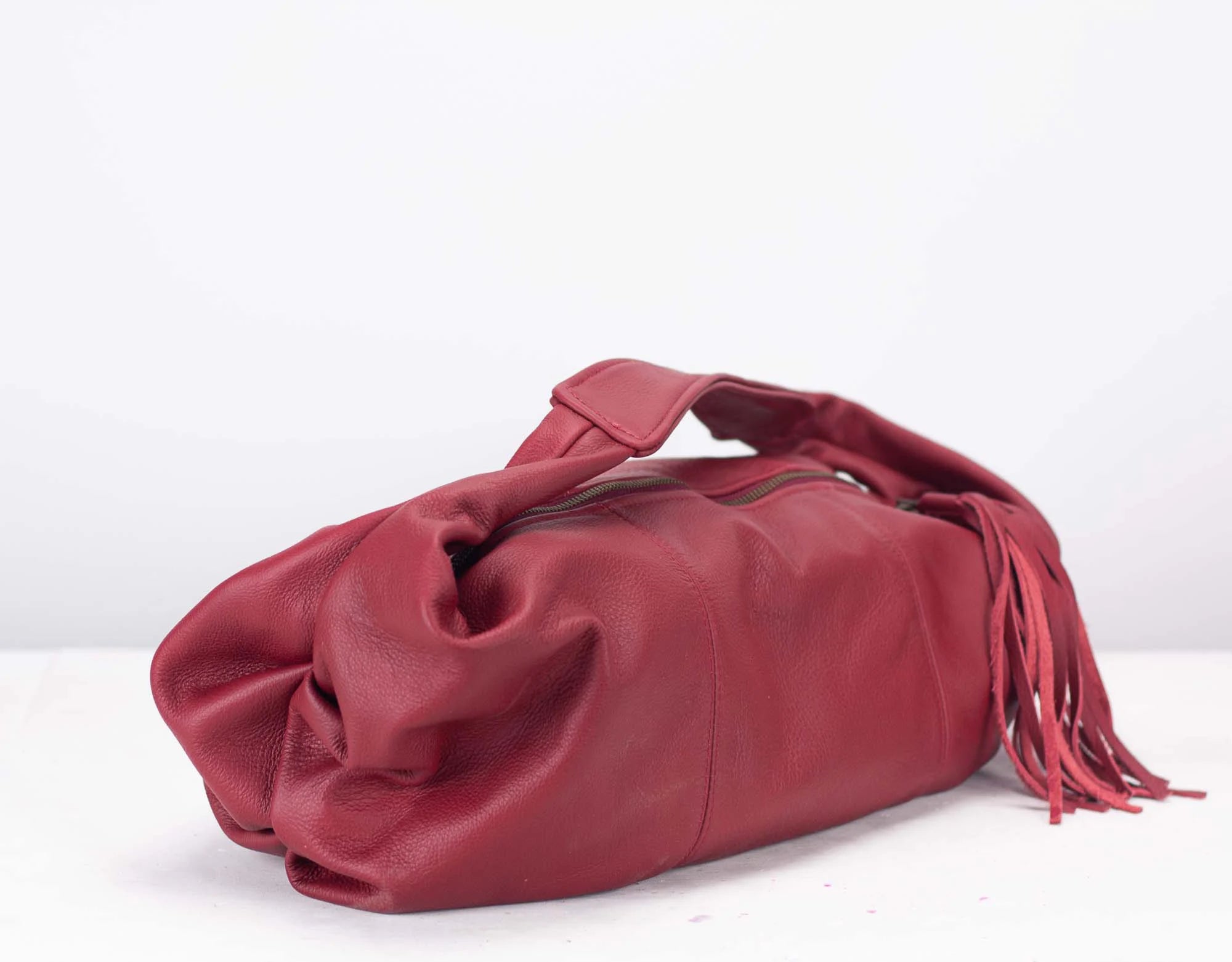 Red leather handbag with fringes on a white background