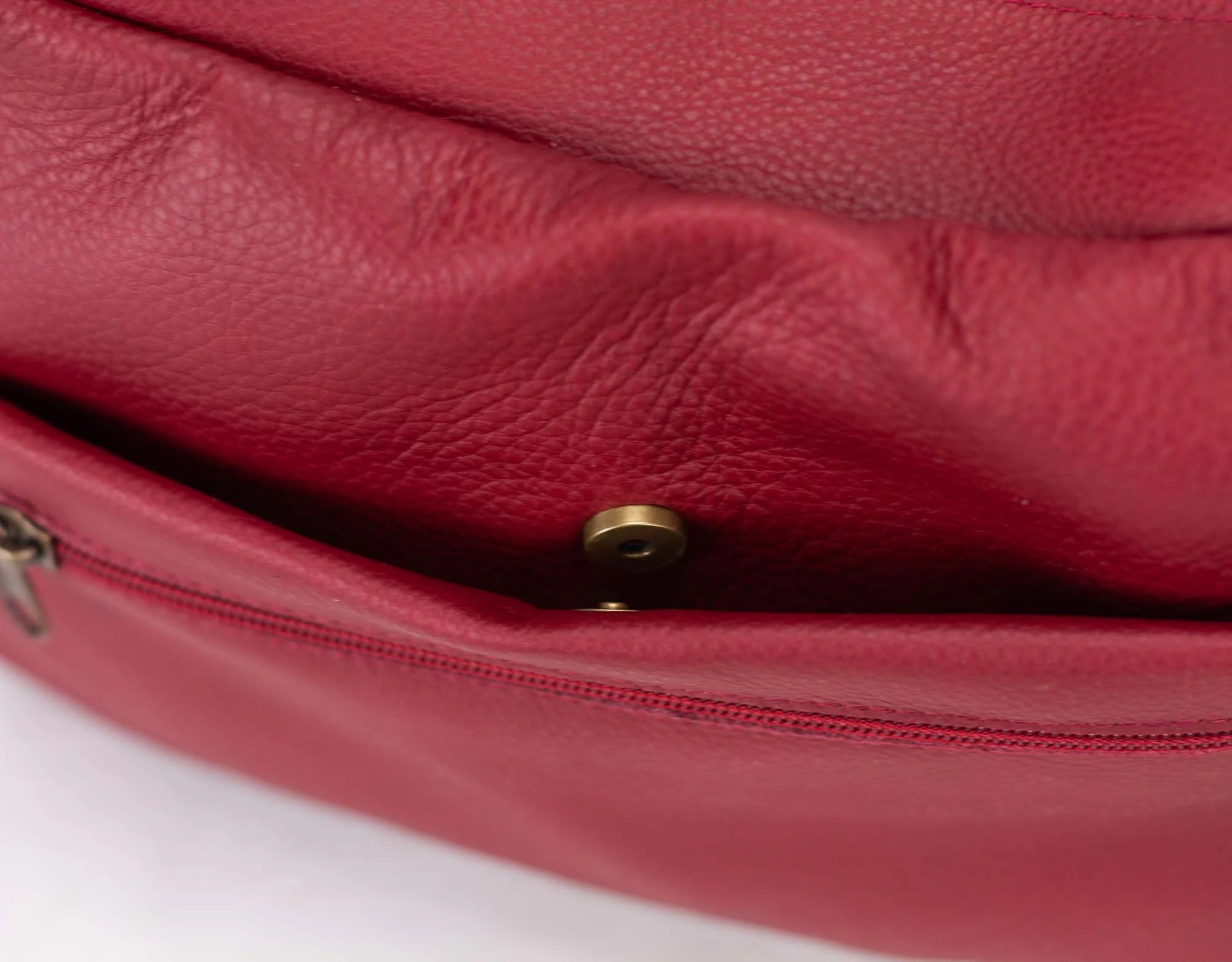 Close-up of a red leather handbag with a gold clasp on a white background