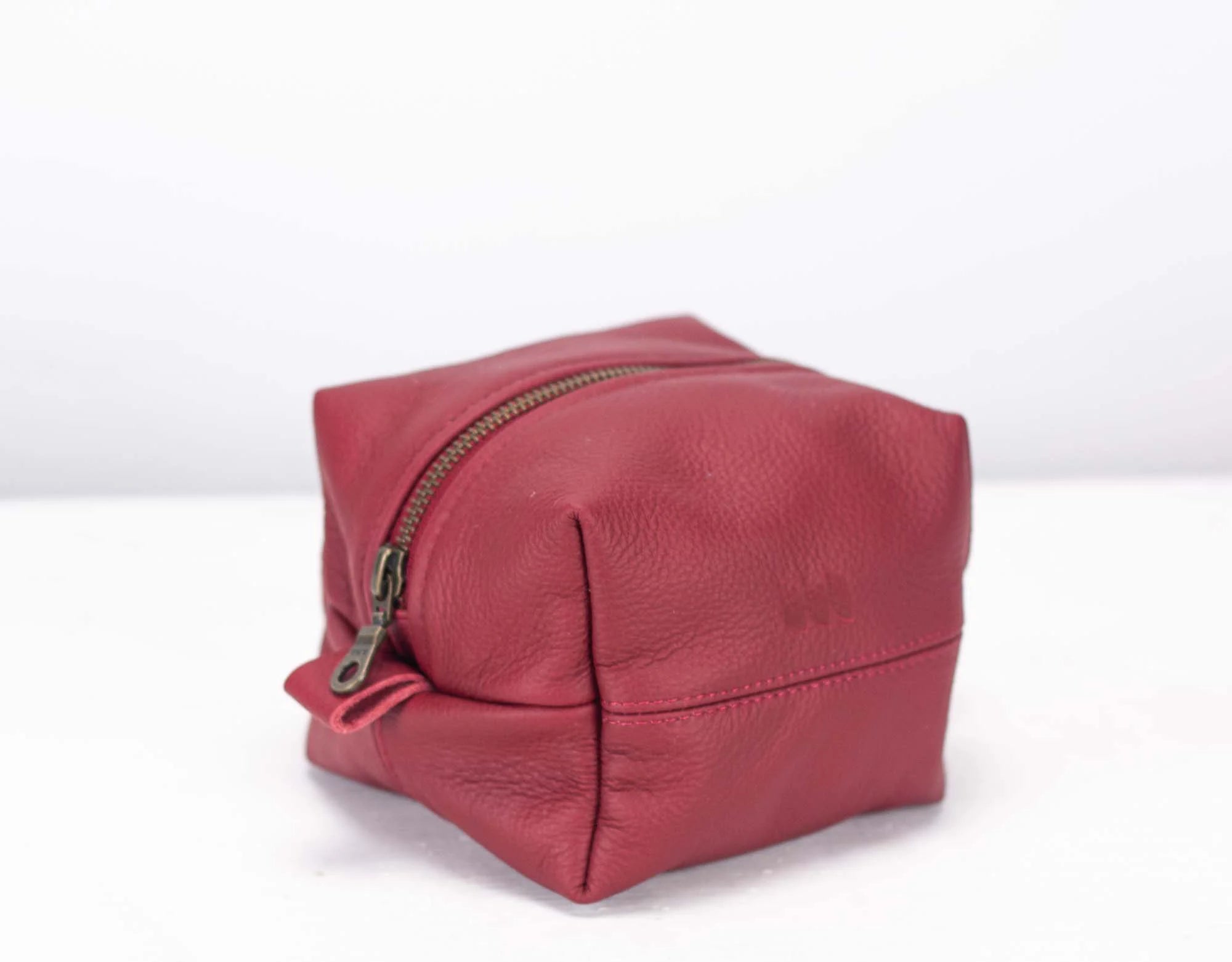 Red leather toiletry bag with a zipper on a white background