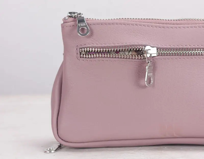 Pink leather bag with zippers on a light gray background