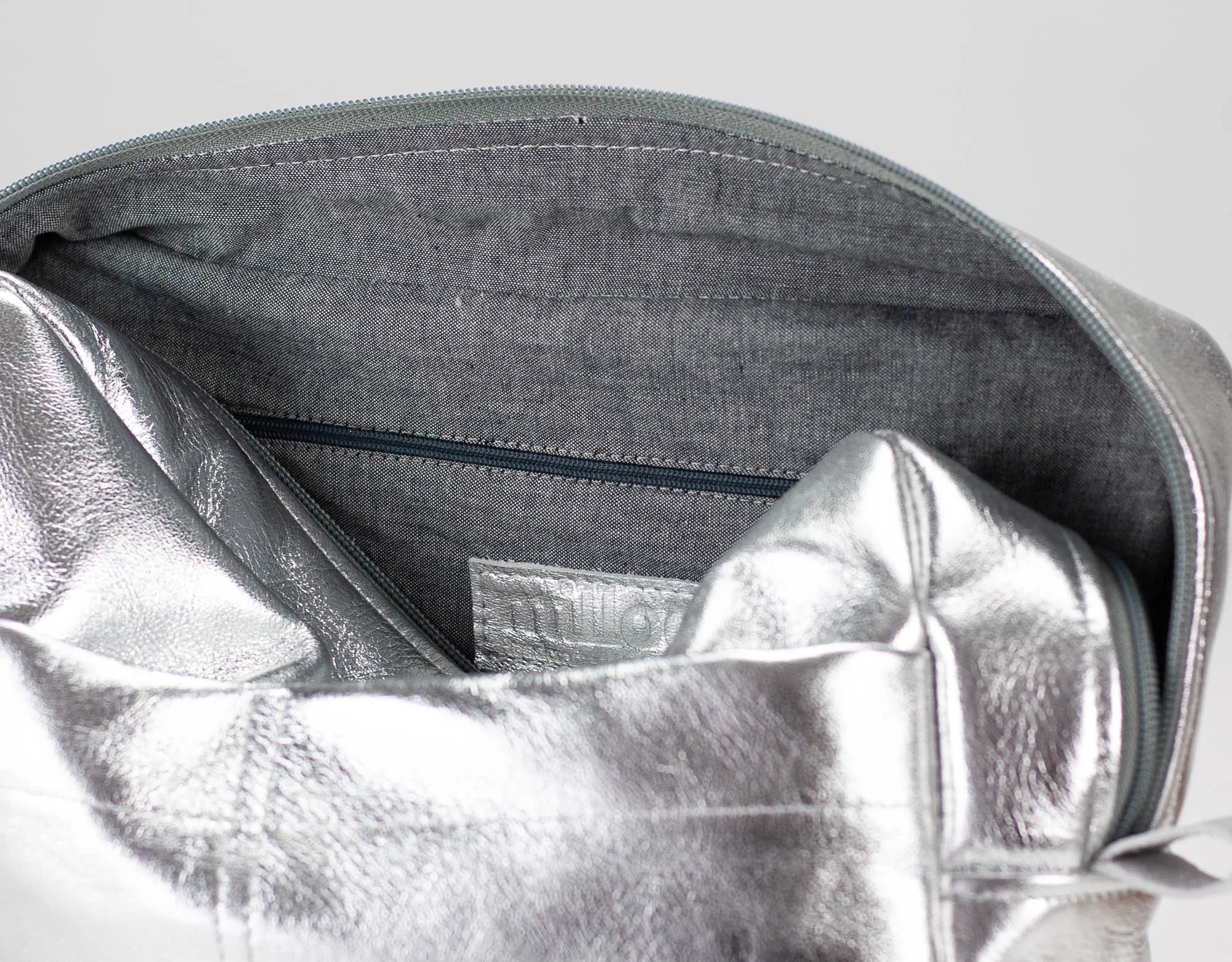 Close-up of a silver metallic pouch inside a gray bag with a visible brand label.