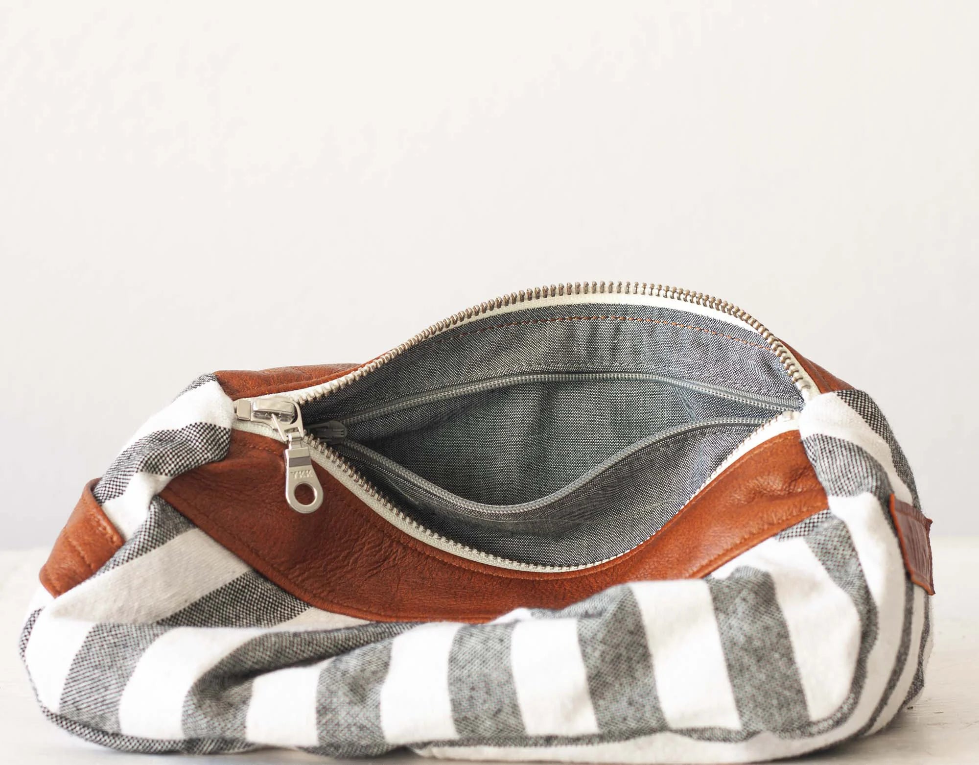 Striped pouch with brown leather patch on a white background