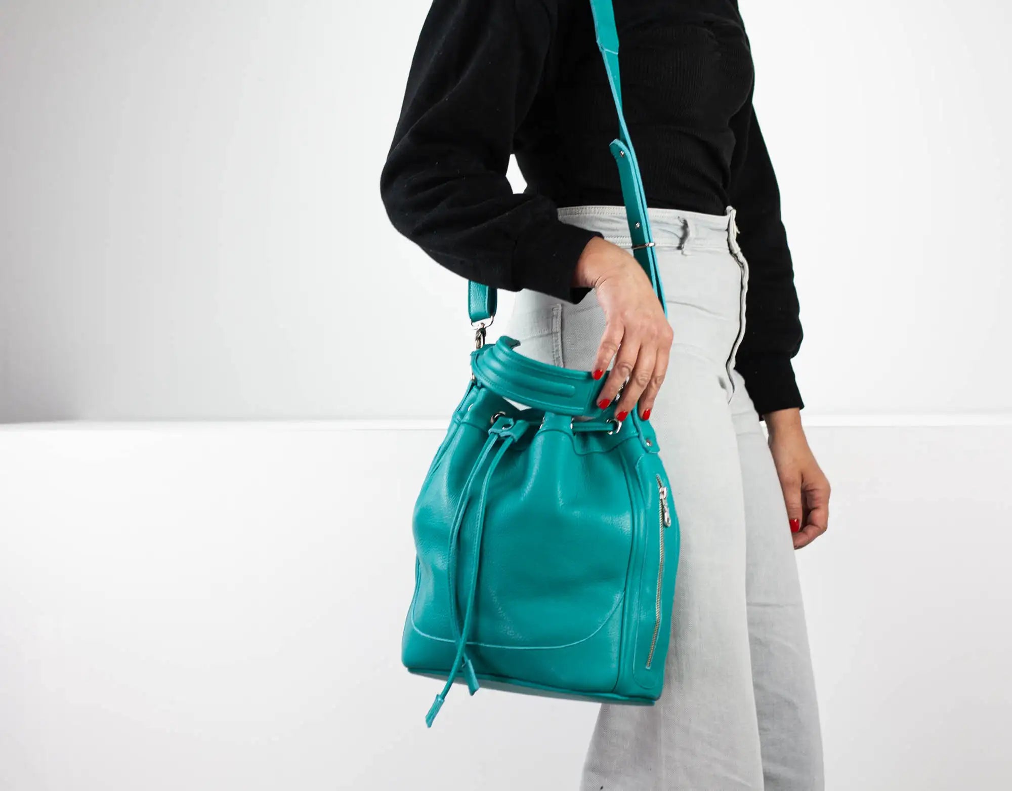 Person holding a teal backpack against a white background