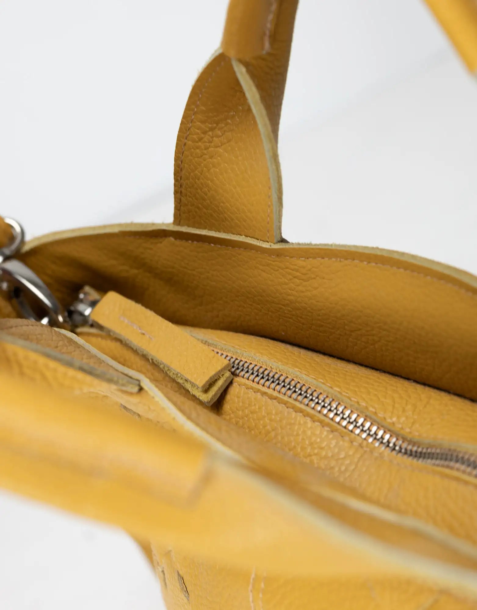 Close-up of a yellow leather bag with a zipper on a white background