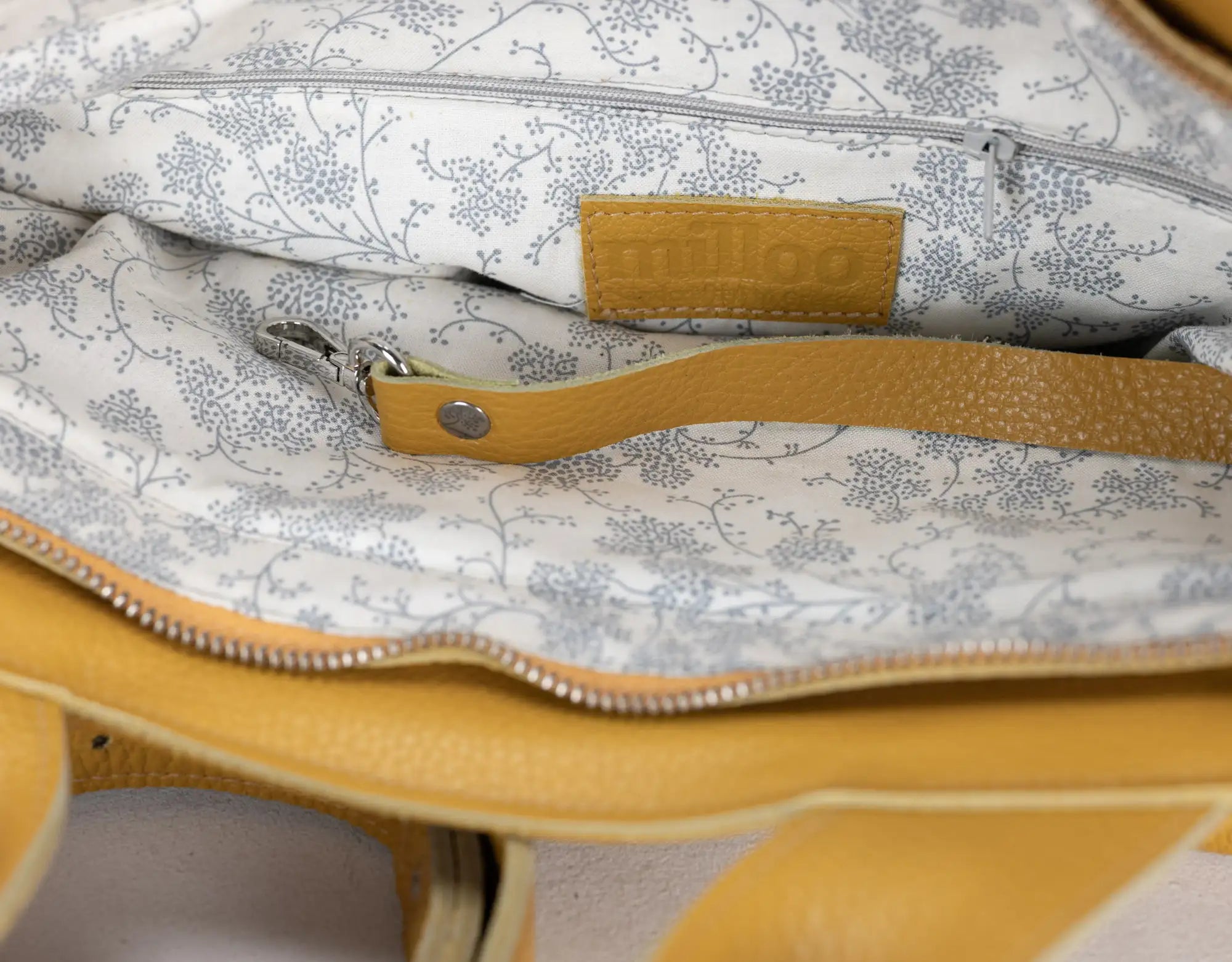 Close-up of a bag with floral pattern and visible brand name on a plain background
