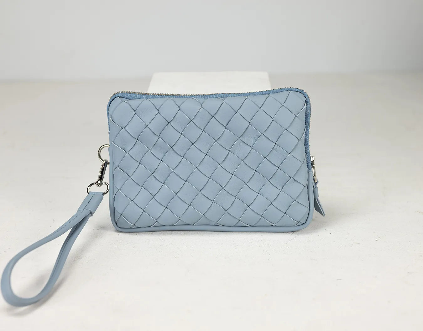 Light blue quilted clutch bag on a white background