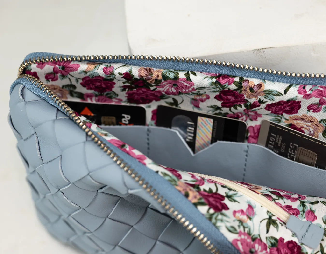 Blue textured clutch with floral lining on a white background