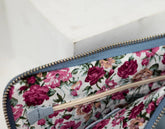 Floral-patterned clutch with a textured blue interior on a white background