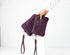 Purple quilted clutch with wrist strap held by a hand on a white background