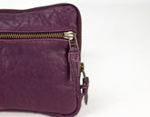 Purple leather bag with gold zipper on a white background